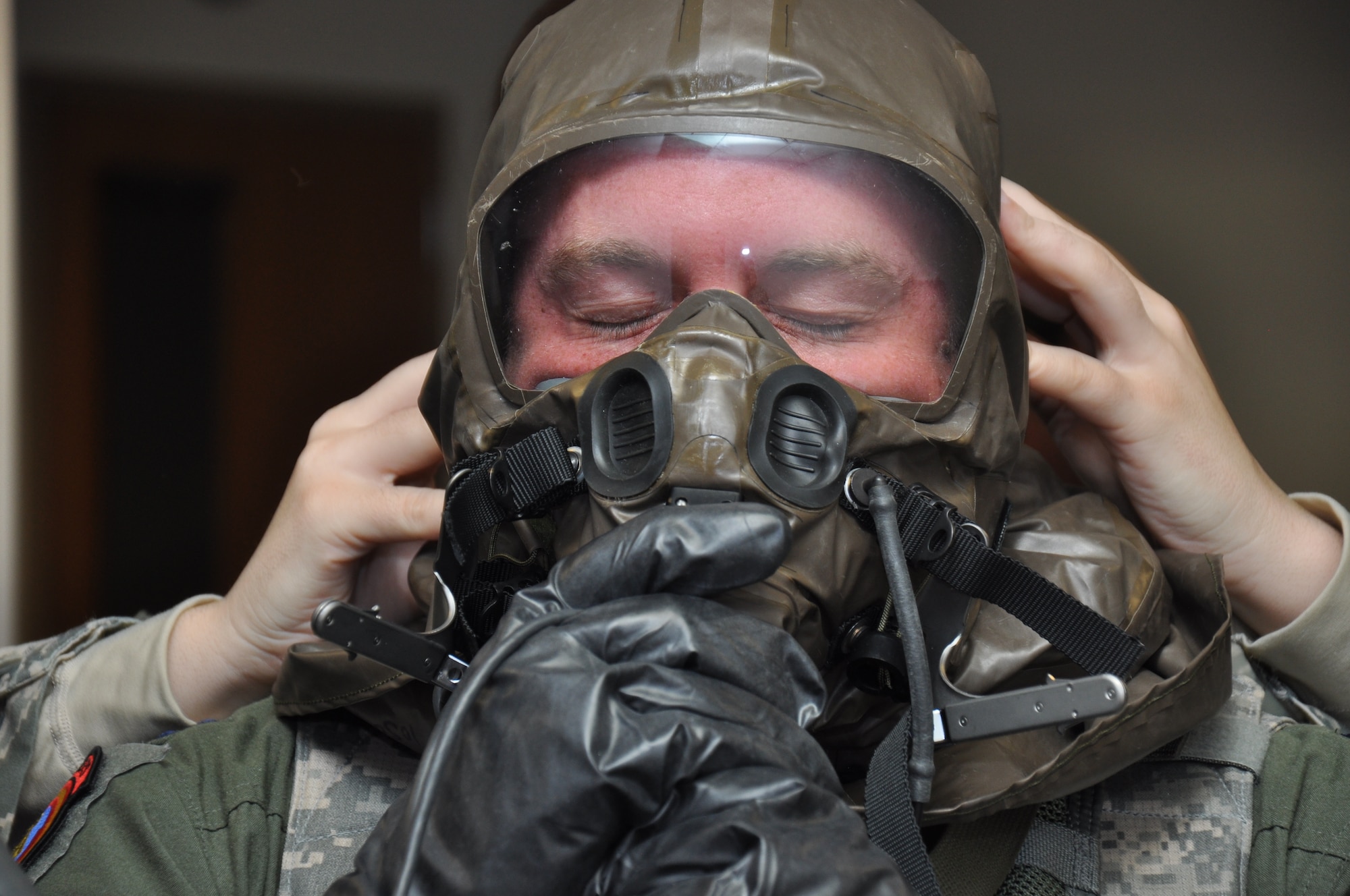 Capt. Jamie Leenman, 21st Airlift Squadron pilot, adjusts the seal on his aircrew chemical defense equipment with the help of Staff Sgt. Iva Marshall, 60th Operations Support Squadron aircrew flight equipment technician, March 4 at Travis. (U.S. Air Force photo/Staff Sgt. Christopher Carranza)