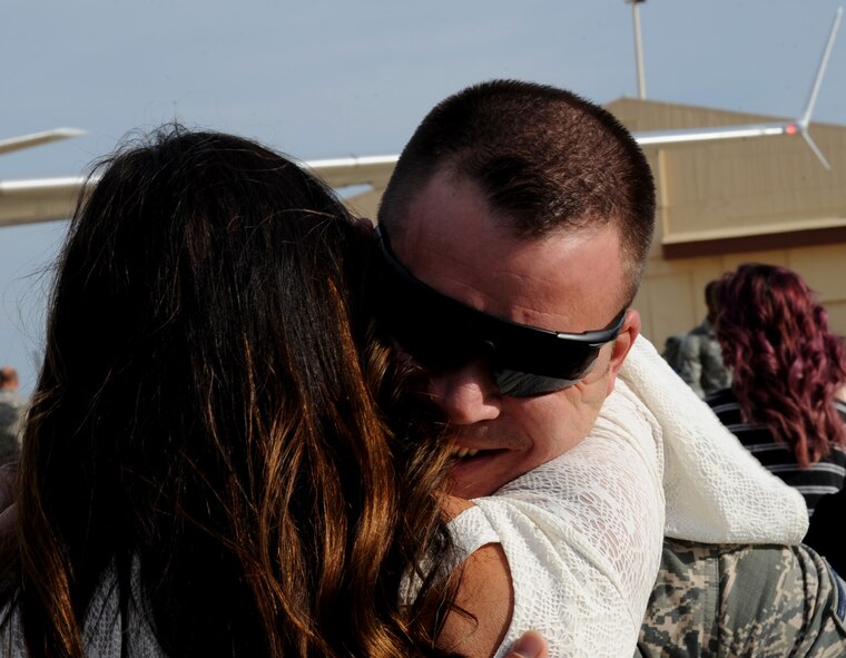 An Airman hugs his wife on Barksdale Air Force Base, March 7, 2014. Airmen assigned to the 2nd Bomb Wing, were returning from a six month deployment to Andersen Air Force Base, Guam, in support of the Continuous Bomber Presence. (U.S. Air Force photo/Staff Sgt. Sean Martin)