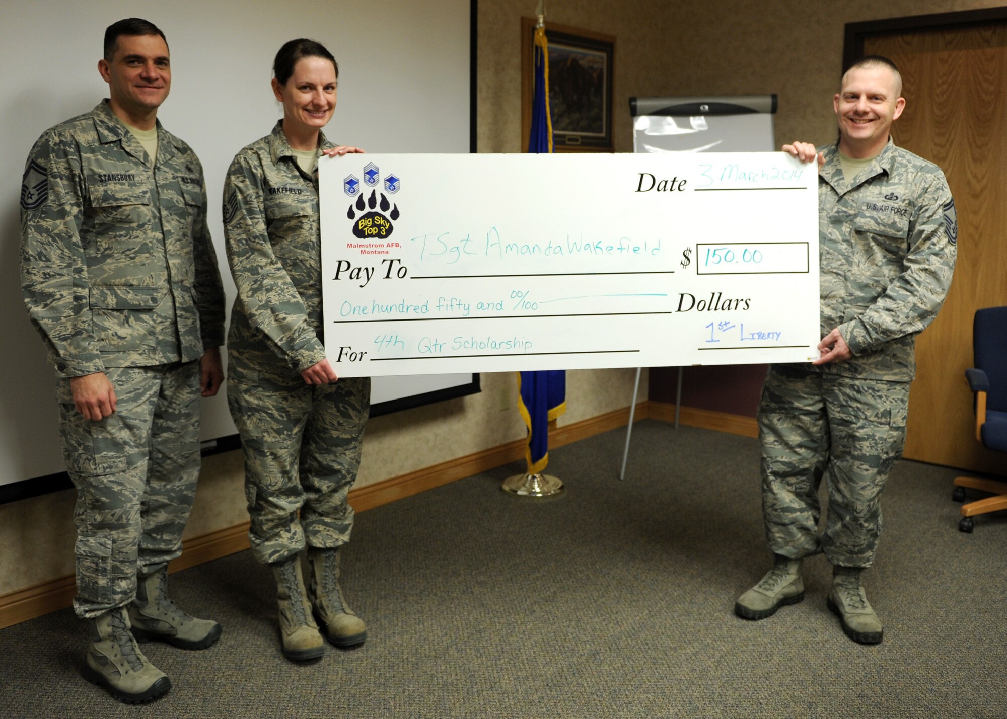 Tech. Sgt. Amanda Wakefield, 819th RED HORSE Squadron member (center left), receives a check from Senior Master Sgts. Paul Stansbury, 341st Security Forces Group Tactical Response Force operations superintendent (left), and William Kudrna, 341st Comptroller Squadron superintendent, at the RED HORSE command building March 5. Wakefield was the Airman recipient of the Big Sky Top 3 Association fourth quarter scholarship for her essay regarding the upcoming enlisted performance report changes. The Top 3 Association offers quarterly scholarships to personnel ranked airman basic through technical sergeant. (U.S. Air Force photo/Senior Airman Katrina Heikkinen)