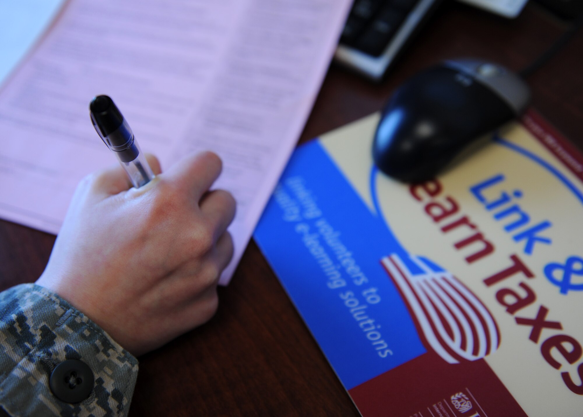 A tax center volunteer signs an interview sheet before preparing an Airman’s taxes. Airmen can get their free tax returns at the center by walk-in or by scheduling an appointment by calling 731-2878. (U.S. Air Force photo/Senior Airman Katrina Heikkinen)