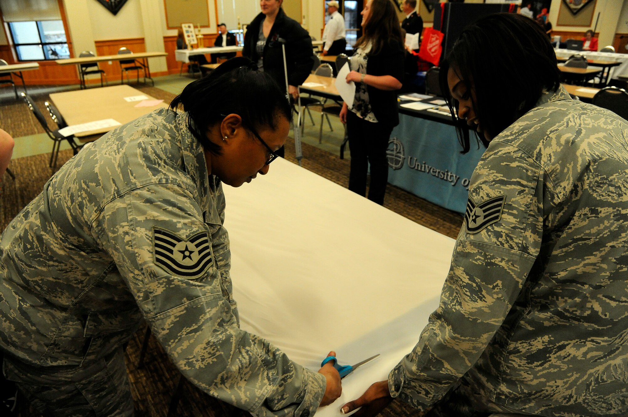 Tech. Sgt. Digna May, 341st Operations Support Squadron personnel reliability program group coordinator (left), and Staff. Sgt. Yolanda Callens, 341st Operations Group knowledge operator, help set up display tables for local community members during Malmstrom’s 2014 Community Fair on March 7 at the Grizzly Bend. Callens and May were two of 35 Team Malmstrom members who volunteered to help during the community fair. (U.S. Air Force photo/Airman 1st Class Collin Schmidt) 