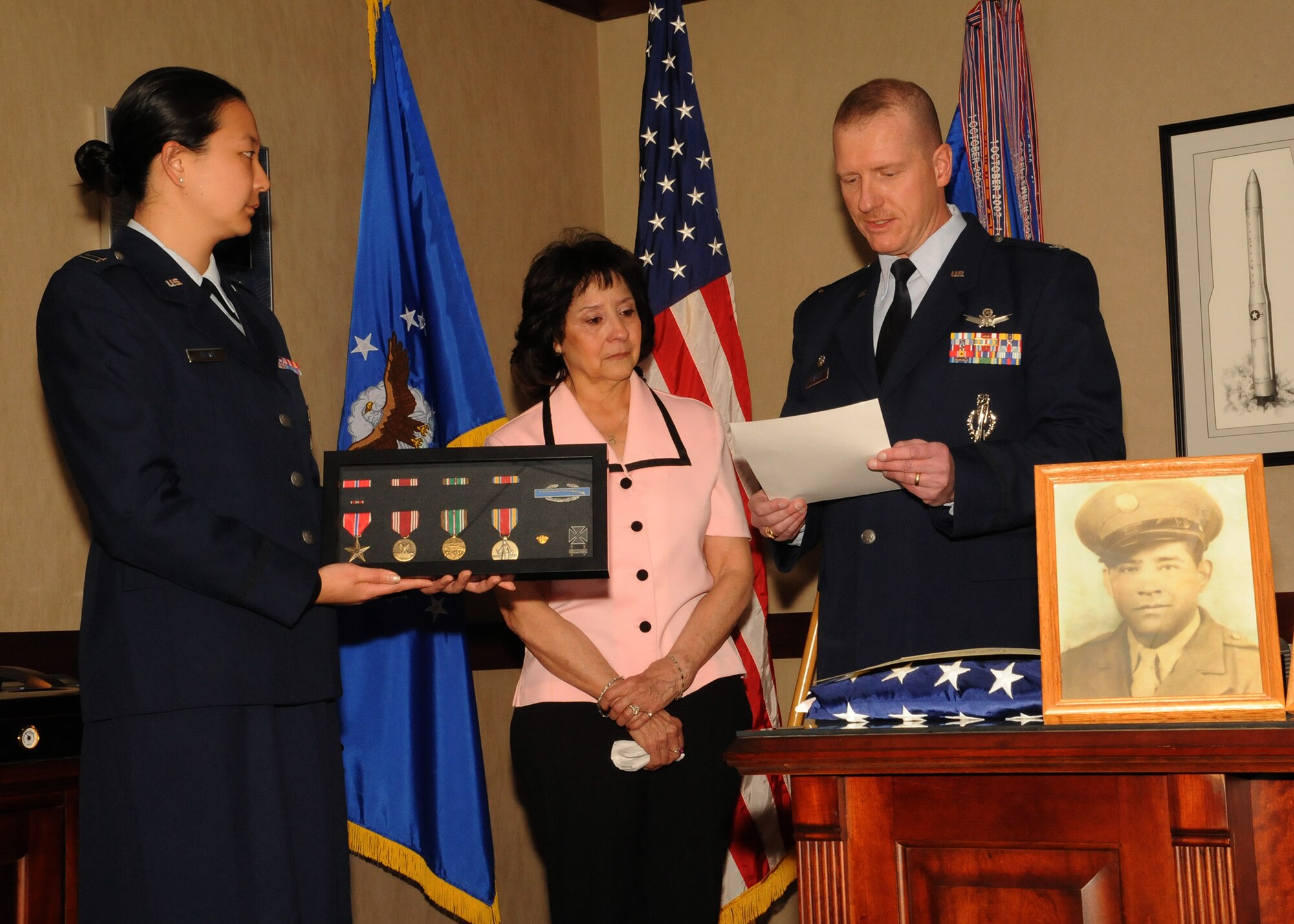 Col. Robert Stanley, 341st Missile Wing commander, reads a citation to Anna Gilmore (center), which outlines her father’s service and earned medals, as Capt. Jessica Tiffany, 341st MW executive officer, holds a display with all the medals in it during a small ceremony in Stanley’s office March 11. A photo of Anna’s father, Jose Elguezabal, sits in front of them. Most of Elguezabal’s military documents were burned in a fire in 1973, but with help from Sen. John Walsh’s office, Anna was able to receive some of her father’s medals nearly 10 years after his death. (U.S. Air Force photo/Senior Airman Cortney Paxton)
