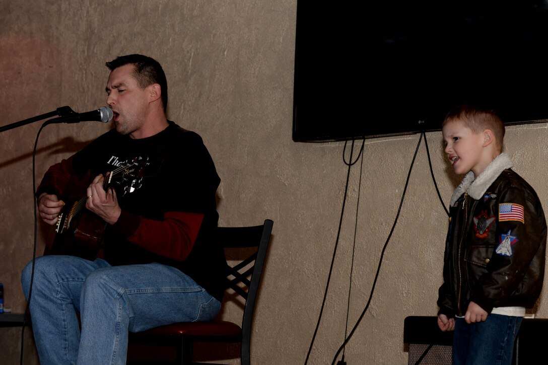 Tech. Sgt. Elliot Benton, 28th Operations Support Squadron air traffic control watch supervisor, performs a song with his son, Joseph, during Open Mic Night in the Dakota’s Club at Ellsworth Air Force Base, S.D., March 7, 2014. Open Mic Night is an opportunity for members of team Ellsworth to display their talents in a relaxed environment. (U.S. Air Force photo by Airman 1st Class Rebecca Imwalle/ Released)