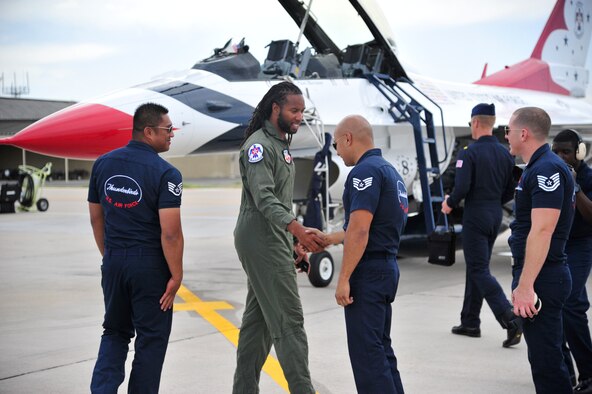 Larry Fitzgerald, Arizona Cardinals wide reciever, is greeted by members of the U.S. Air Force Thunderbirds March 13 as he makes his way to the jet he will be flown in at Luke Air Force Base, Ariz. The Thunderbirds are scheduled to perform at approximately 3 p.m. on March 15 and 16 at Luke's Open House and Air Show. (U.S. Air Force photo by Senior Airman Grace Lee)