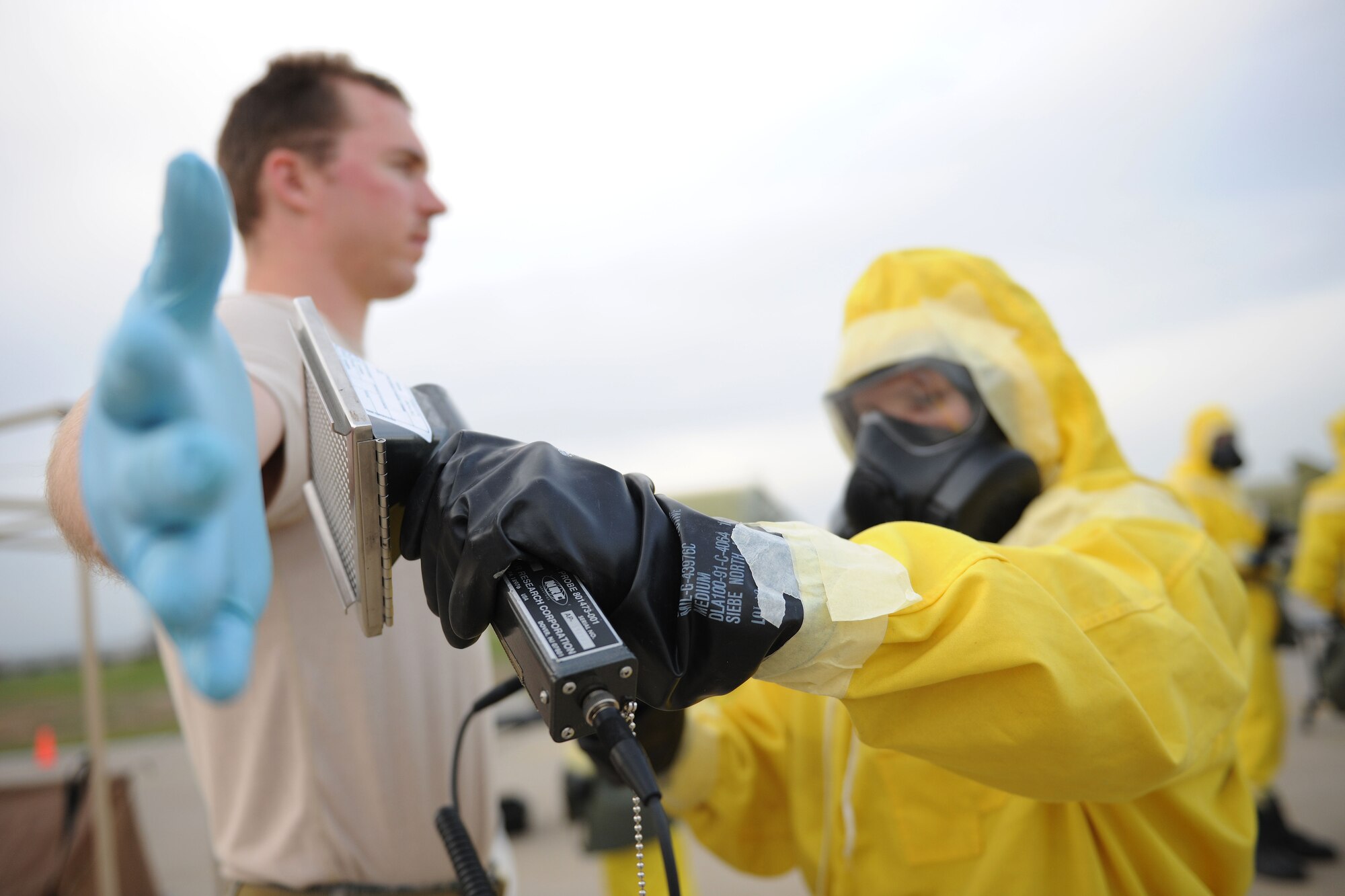 An Airman dressed in an anti-contamination suit scans Staff Sgt. Matthew Thompson, 39th Civil Engineer Squadron explosive ordnance disposal technician, for hazardous substances after entering a contamination control station during a training exercise March 12, 2014, Incirlik Air Base, Turkey.  Airmen assigned to the 39th EOD squadron along with other first responders reported to the scene for an emergency response training day. (U.S. Air Force photo by Senior Airman Nicole Sikorski/Released)