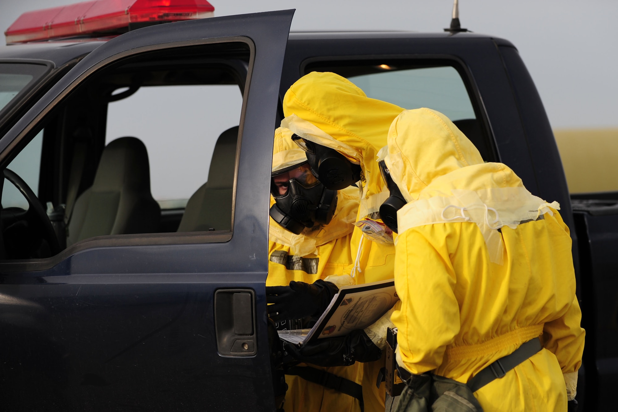 Airmen dressed in anti-contamination suits go through a checklist before scanning a vehicle for hazardous materials during an exercise March 12, 2014, Incirlik Air Base, Turkey.  All personnel and items must be scanned for contaminants after entering a contaminated area. (U.S. Air Force photo by Senior Airman Nicole Sikorski/Released)