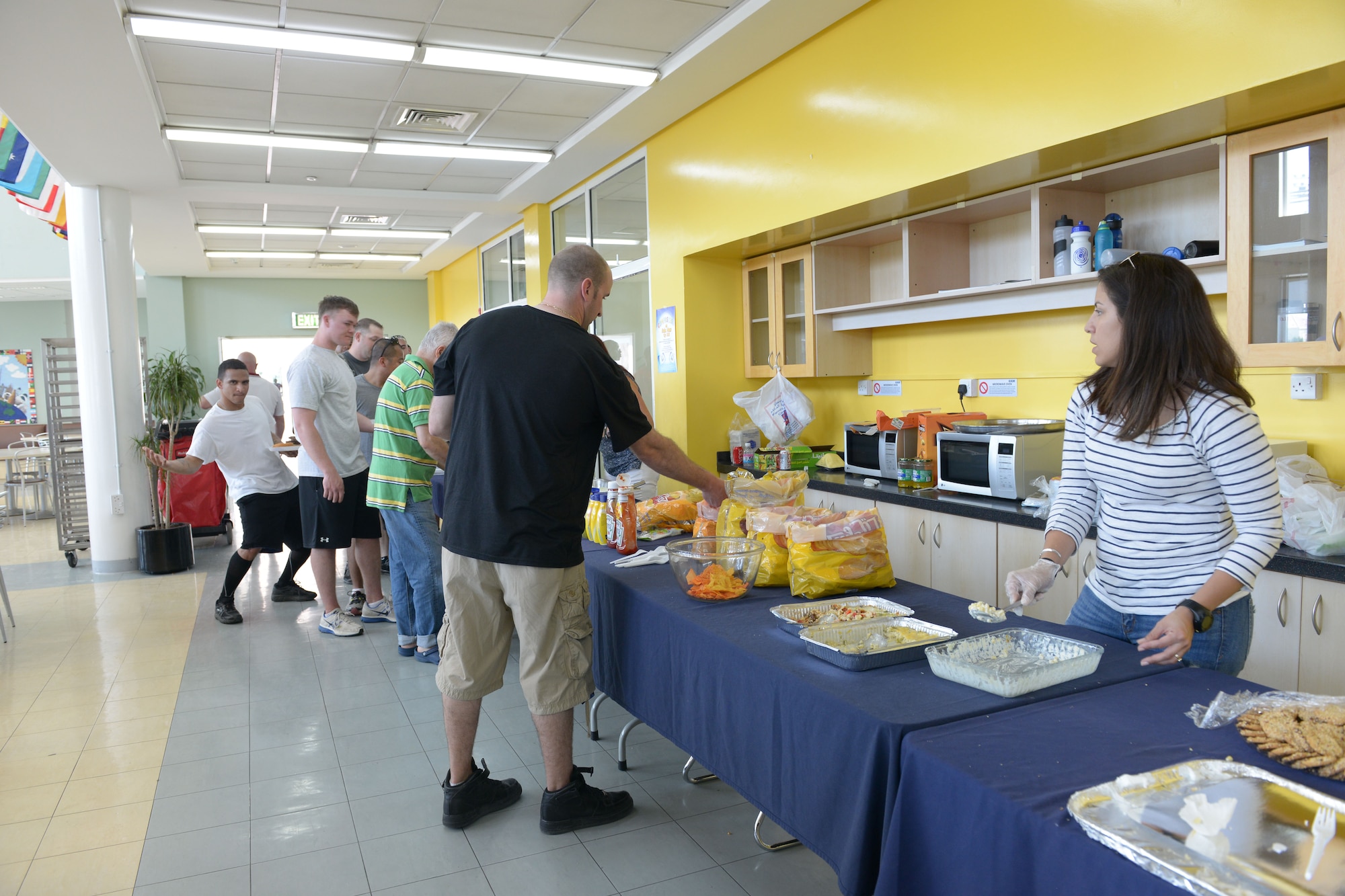 Airmen, Marines, Sailors and Soldiers line up for lunch to enjoy burgers and shawarmas provided by the American School of Doha in Qatar, during Military Appreciation Day, Mar. 7, 2014. Through the 379th Air Expeditionary Wing’s private organization Jar Saleh, Arabic for ‘Good Neighbor,’ both the 379th AEW at Al Udeid Air Base, Qatar, and the Area Support Group at Camp As Sayliyah, Qatar, have been heavily involved at ASD through a variety of volunteer opportunities. The American School of Doha showed their appreciation by hosting the 4th annual Military Appreciation Day for the Airmen, Soldiers, Sailors and Marines deployed to AUAB and CAS.  (U.S. Air Force photo/Senior Airman Hannah Landeros)