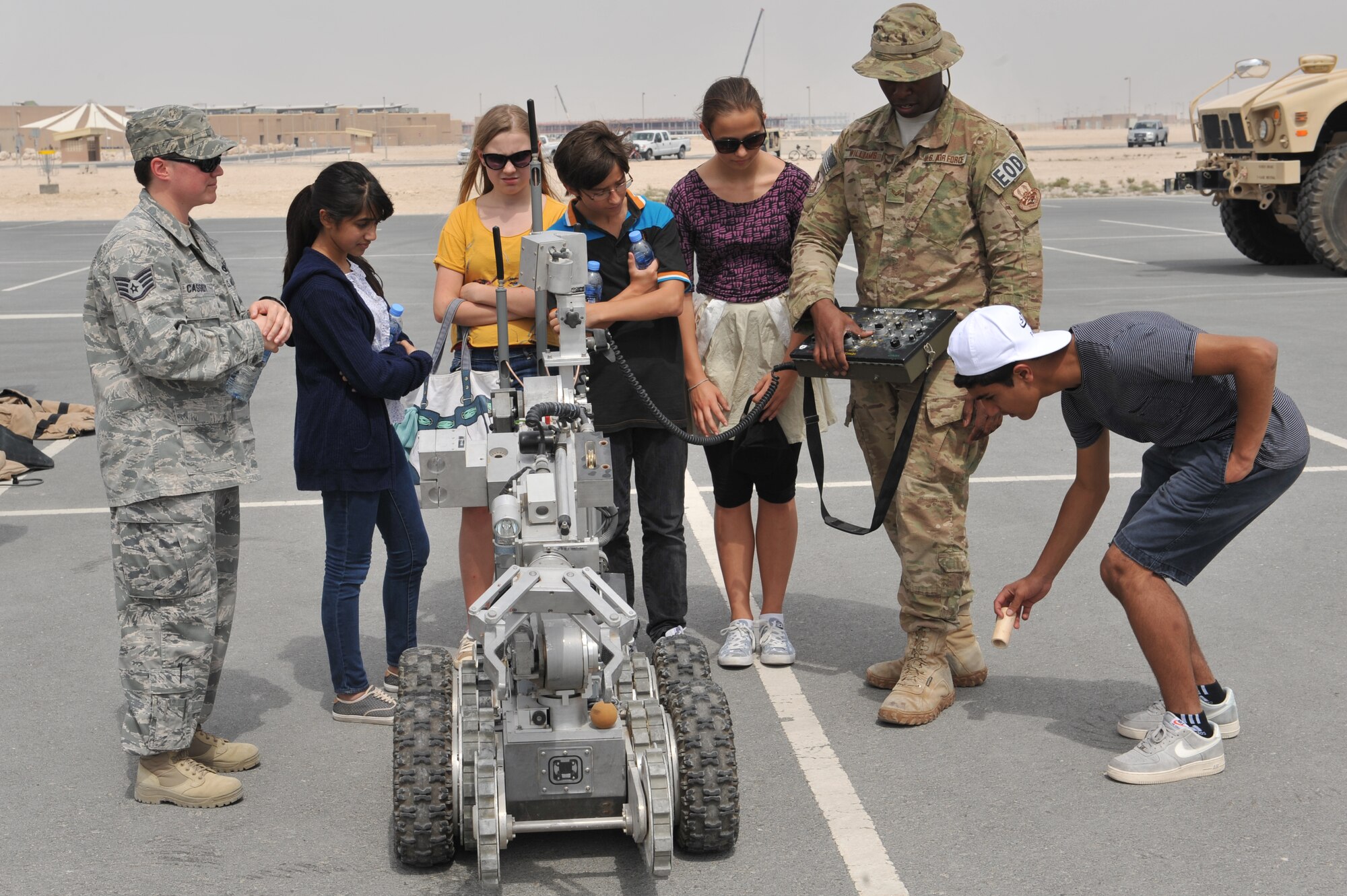 Senior Airman Joel Williams (right) demonstrates the use of a Remotec ANDROS F6A heavy-duty robot during the American School of Doha’s third annual 8th grade field trip to Al Udeid Air Base, Qatar, Mar. 10, 2014. The 379th Air Expeditionary Wing hosted a field trip for students showcasing the variety of careers available to Airmen. Around 150 students came to the base to see how Airmen live, where they work and exactly what they do. The F6A robots speed and agility make it a choice for a wide range of missions. Staff Sgt. Tammy Cassidy (left) escorts students during the visit and highlights the mission. Williams is a 379th Expeditionary Civil Engineer Squadron Explosive Ordnance Disposal technician deployed from Travis Air Force Base, Calif., and a Puyallup, Wash., native. Cassidy is a 379th AEW Check Six facilitator and is deployed from Altus AFB, Okla., and a native of Woonsocket, R.I. (U.S. Air Force photo by Master Sgt. David Miller)