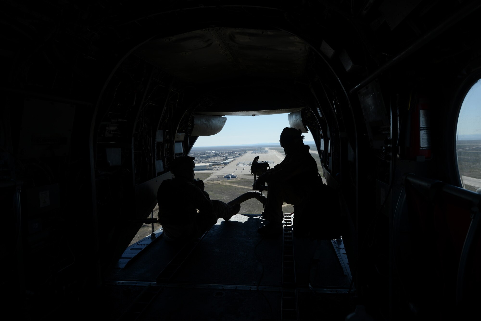 Two military members sit at the tail-end of a CH-46 Sea Knight helicopter as it takes off March 13, 2014, from Mountain Home Air Force Base, Idaho. Marines from the 3rd Marine Aircraft Wing at Marine Corps Air Station Miramar, Calif., are currently at MHAFB participating in Gunfighter Flag. Military aircraft and personnel from the U.S. Air Force, U.S. Marine Corps and British Royal Army are performing exercise combat operations throughout the week while participating in Gunfighter Flag. The exercise is designed to prepare multiple joint and coalition terminal attack controller teams for upcoming deployments as well as provide proficiency training for aircrews. (U.S. Air Force photo by Senior Airman Benjamin Sutton/Released)