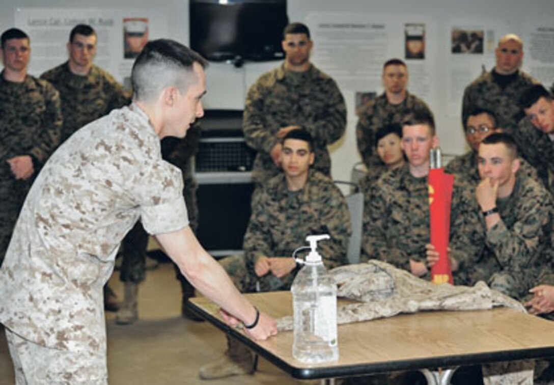 Marine Staff Sgt. Christopher Kirby, marshal arts instructor trainer and Chemical, Biological, Radiological and Nuclear defense instructor, teaches Marines Awaiting Training how to properly roll up the sleeves of their summer uniforms. Marines went sleeves-up Sunday, after a more than two-year-old sleeves- down policy was rescinded by the commandant of the Marine Corps. The bottle is for securing the uniform while rolling up the sleeve.