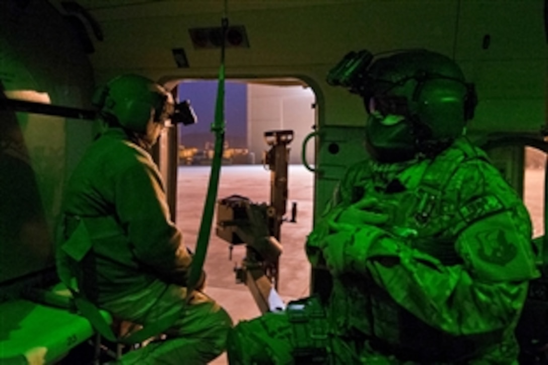 As seen through a night-vision device, U.S. Air Force Tech Sgt. Robert Smeaton, right, and an Afghan air force Mi-17 aerial gunner prepare to fly a night training mission in Kabul, Afghanistan, March 13, 2014. Smeaton is assigned to the 438th Air Expeditionary Wing, NATO Air Training Command Afghanistan.