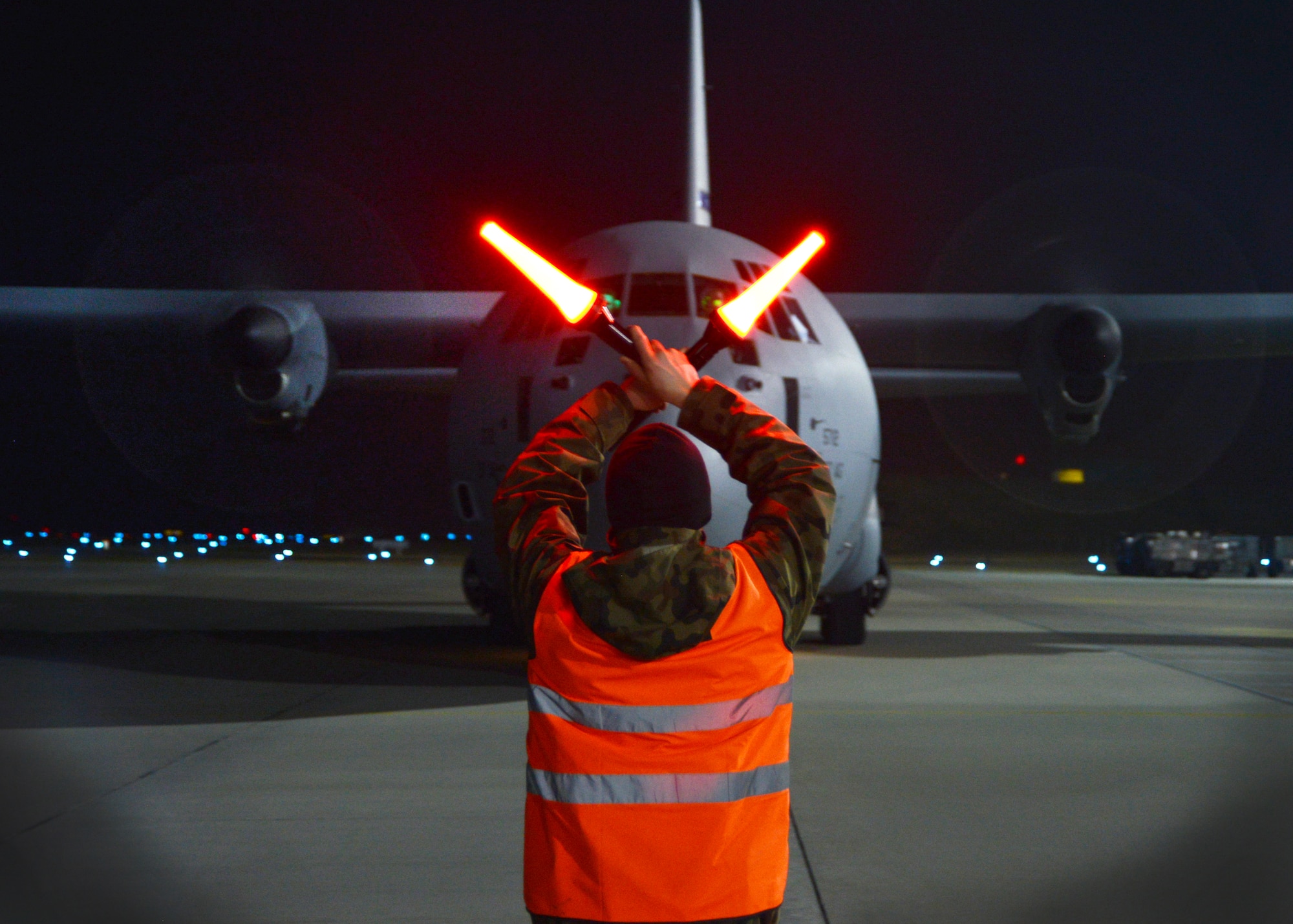 A Polish airman guides a C-130 Hercules assigned to Ramstein Air Base, Germany, onto the flightline, March 13, 2014, at Lask Air Base, Poland. 200 U.S. military personnel arrived in Poland, which demonstrates an enduring partnership with NATO allies. (U.S. Air Force photo/Airman 1st Class Ryan Conroy) 