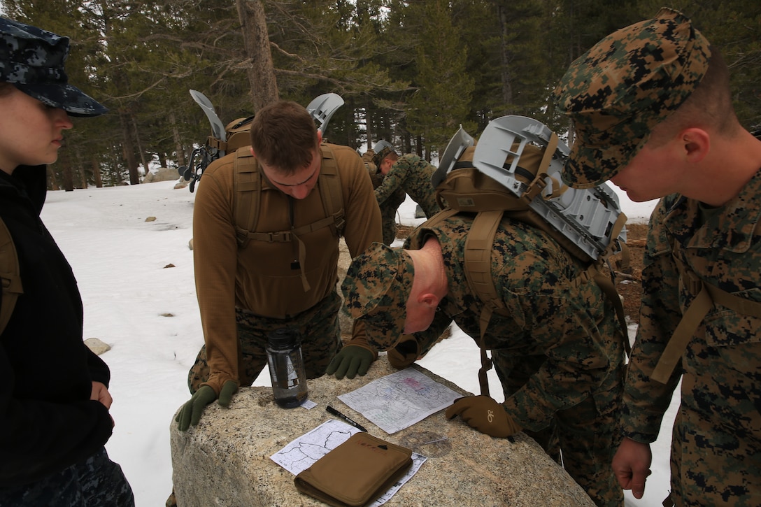 Sgt. Charles Peterson, wireman, Marine Corps Mountain Warfare Training Center, plots a point with his team on a map before heading out for the practical application portion of the land navigation class in the MCMWTC training area, Feb. 26, 2014. The team traversed the area using the "dead reckoning" method of land navigation with a compass.(Official Marine Corps photo by Lance Cpl. Charles Santamaria/Released)