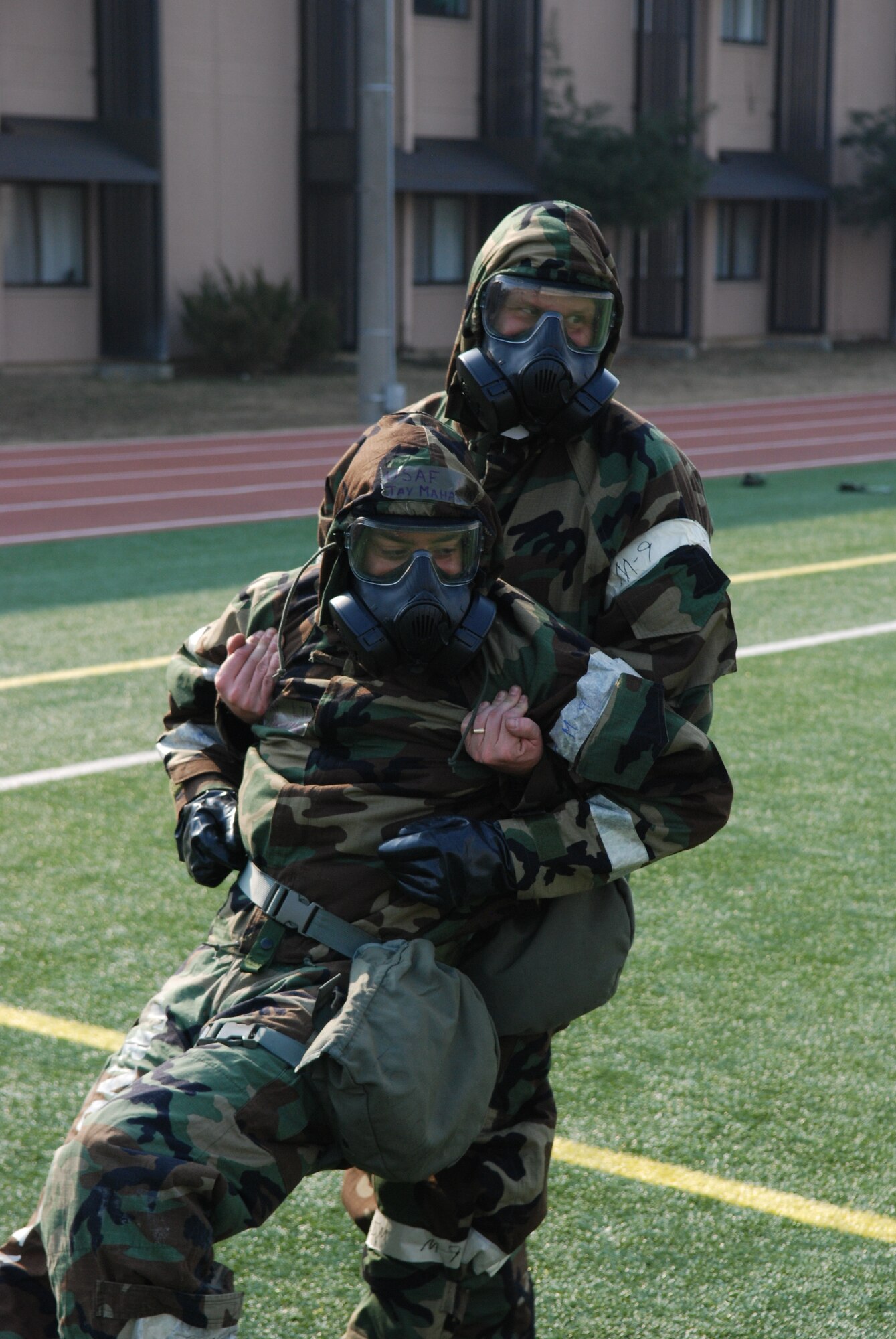 OSAN AIR BASE, Republic of Korea - Members of the 7th Air Force perform a buddy drag during staff PT March 14, 2014. Seventh AF members switched things up a little during their monthly PT session by exercising in their chemical protective gear. Members had to perform a circuit that consisted of push-ups, crunches, low-crawls, rush 'n rolls and buddy carries, ending with a sprint to the finish.  (U.S. Air Force photo by Tech. Sgt. Thomas J. Doscher)