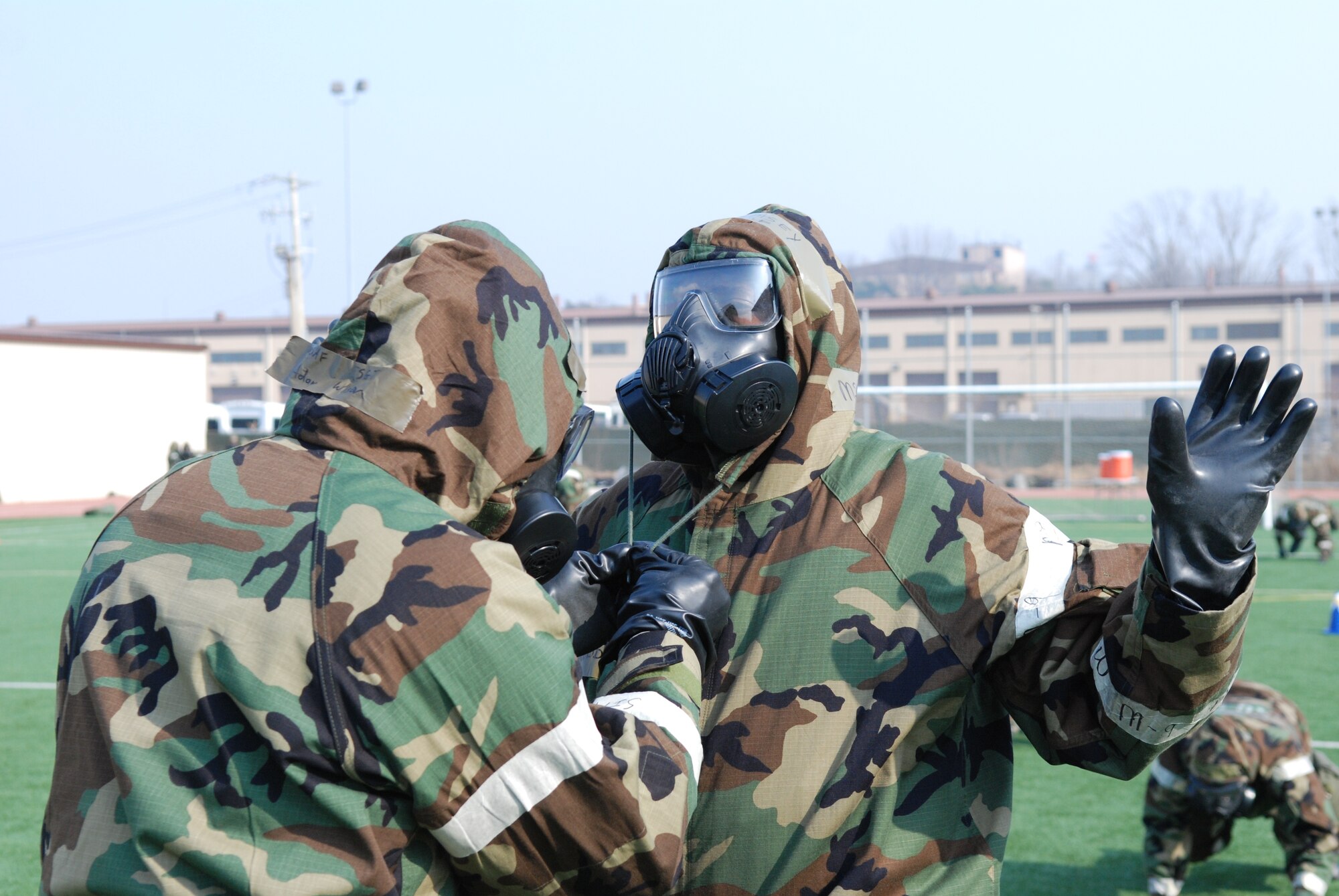 OSAN AIR BASE, Republic of Korea - Members of the 7th Air Force check each other's MOPP gear after performing push-ups during staff PT March 14, 2014. Seventh AF members switched things up a little during their monthly PT session by exercising in their chemical protective gear. Members had to perform a circuit that consisted of push-ups, crunches, low-crawls, rush 'n rolls and buddy carries, ending with a sprint to the finish.  (U.S. Air Force photo by Tech. Sgt. Thomas J. Doscher)