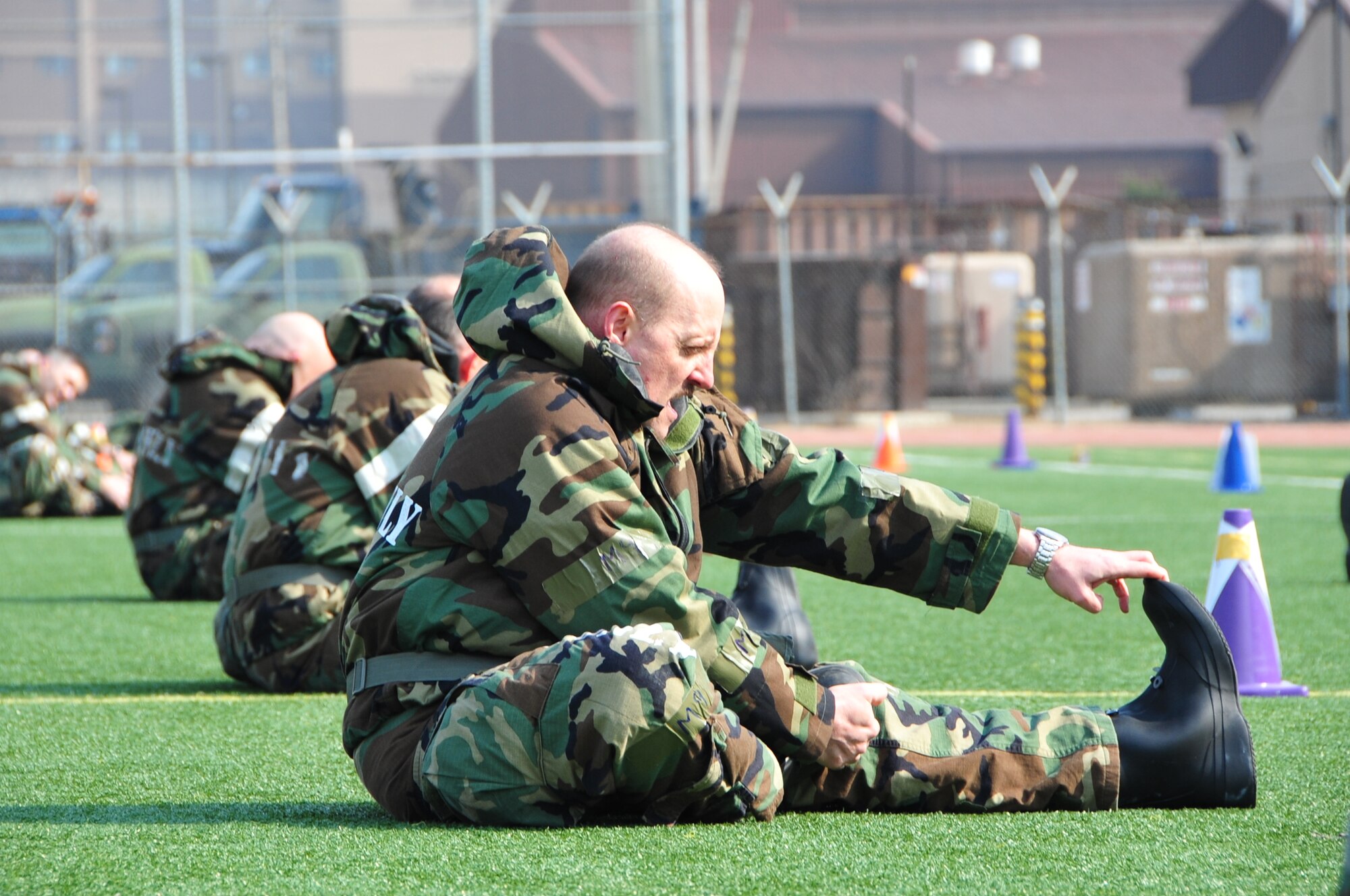 OSAN AIR BASE, Republic of Korea - Lt. Col. Thomas Morea, 7th Air Force A7, stretches out in MOPP 2 before staff PT on Osan Air Base, Republic of Korea, March 14, 2014. Staff-wide PT is a monthly requirement for 7th AF, but this was the first time the unit conducted PT in MOPP gear. Staff members were required to low crawl, rush 'n roll, perform buddy carries, do push-ups, crunches and side-straddle hops. (U.S. Air Force photo by Maj. Richelle Dowdell)