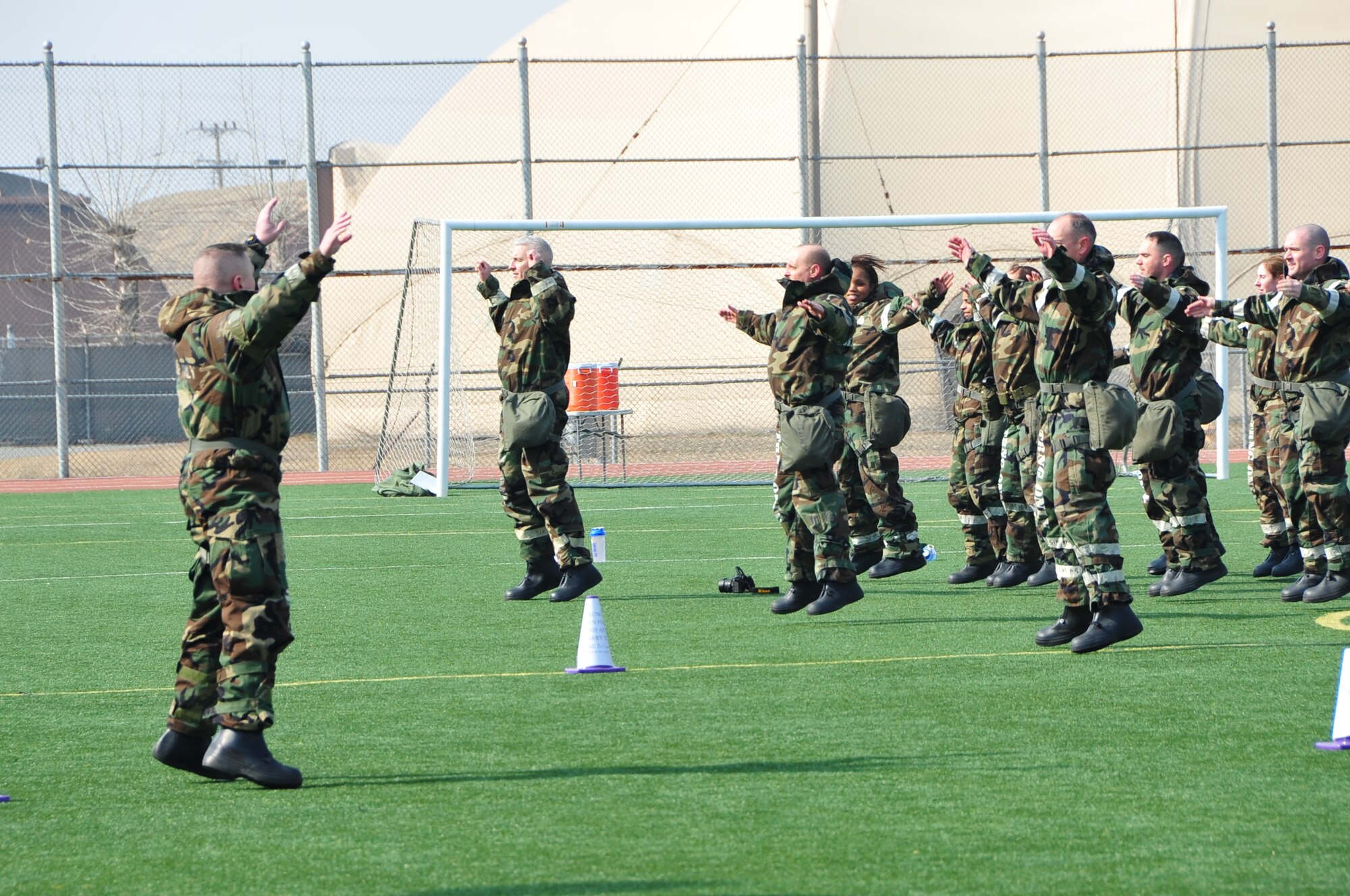 OSAN AIR BASE, Republic of Korea - Chief Master Sgt. Derrick Moniz, 7th Air Force A7, leads the formation during warm-ups at the start of staff PT on Osan Air Base, Republic of Korea, March 14, 2014. Staff-wide PT is a monthly requirement for 7th AF, but this was the first time the unit conducted PT in MOPP gear. Staff members were required to low crawl, rush 'n roll, perform buddy carries, do push-ups, crunches and side-straddle hops. (U.S. Air Force photo by Maj. Richelle Dowdell)
