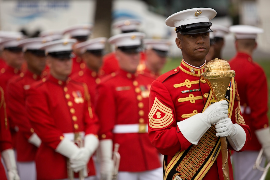 Master Gunnery Sgt. Kevin D. Buckles grips a ceremonial mace while he waits to march the Drum and Bugle Corps onto the Paige Fieldhouse football field for an ensuing musical performance during a 2014 Battle Color Detachment drill exhibition March 13. Commonly referred to as The Commandant's Own, the Drum and Bugle Corps performed choreographed marching routines. The Drum and Bugle Corps’ are easily distinguished by their scarlet dress uniform coats and white trousers. Buckles is the drum major for the Marine Corps Drum and Bugle Corps.