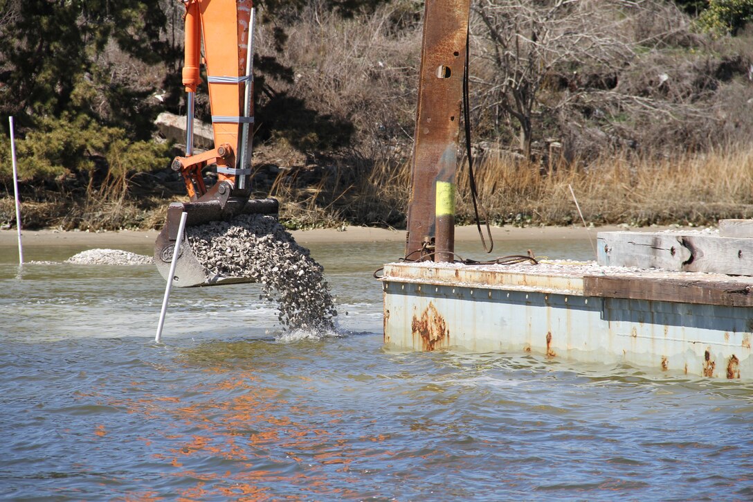 A crane moves 14,000 fossilized oyster shell from a barge into waters in the Lafayette River. This Norfolk International Terminal six-acre sanctuary reef is one of six reefs being constructed as part of the Craney Island Eastward Expansion project/oyster mitigation process. The oyster reefs will be complete in June 2014. All of the reefs will be permanent oyster sanctuaries. 
