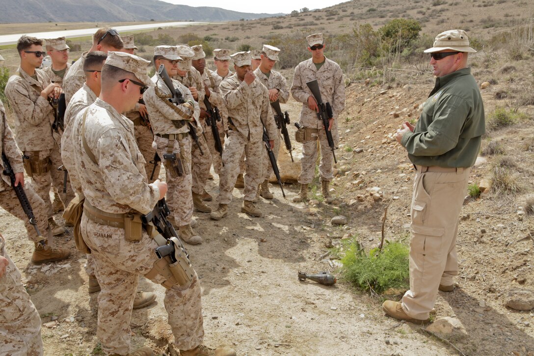 Marines with 1st Law Enforcement Battalion gather around an instructor to learn about traditional improvised explosive devices placement aboard Marine Corps Base Camp Pendleton, Calif., March 11. The Marines were sent through IED lanes to practice spotting and identifying IED indicators.