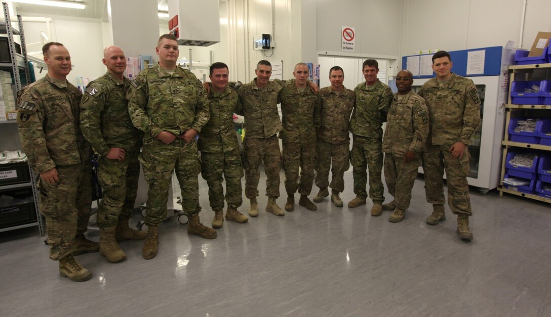 Operation Proper Exit participants pose for a photo with soldiers who work in the Operating Room of Camp Bastion's hospital in Helmand province, Afghanistan, March 13, 2014. Operation Proper exit is a program for wounded service members who choose to come back to Afghanistan after recovering from combat injuries in order to find closure.