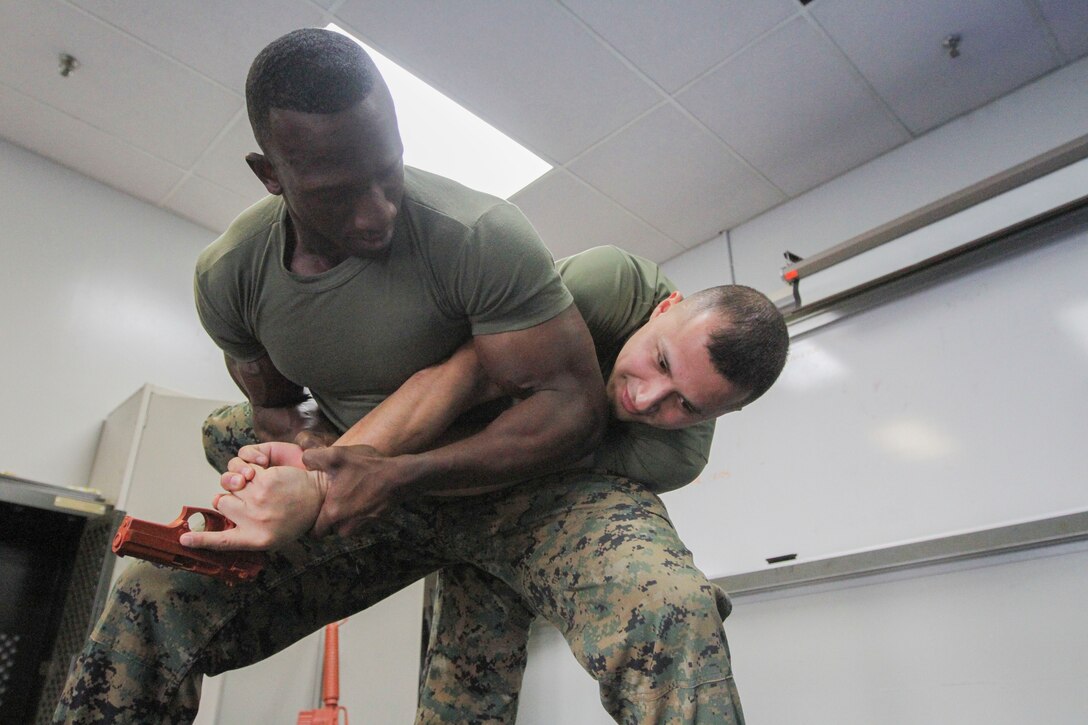 GARDEN CITY, N.Y. - Sgt. Malik S. King, a purchasing agent, warehouse chief, color sergeant, and now martial arts instructor for the 1st Marine Corps District and a native of Hempstead N.Y., demonstrates a disarming technique with Sgt. Edgar Caballero, an Austin, Texas, native now a legal clerk assigned to 1MCD on Feb. 12 in the unit's headquarters. King graduated the Martial Arts Instructor Course in January. (U.S. Marine Corps photo by Lance Cpl. Brandon Thomas).