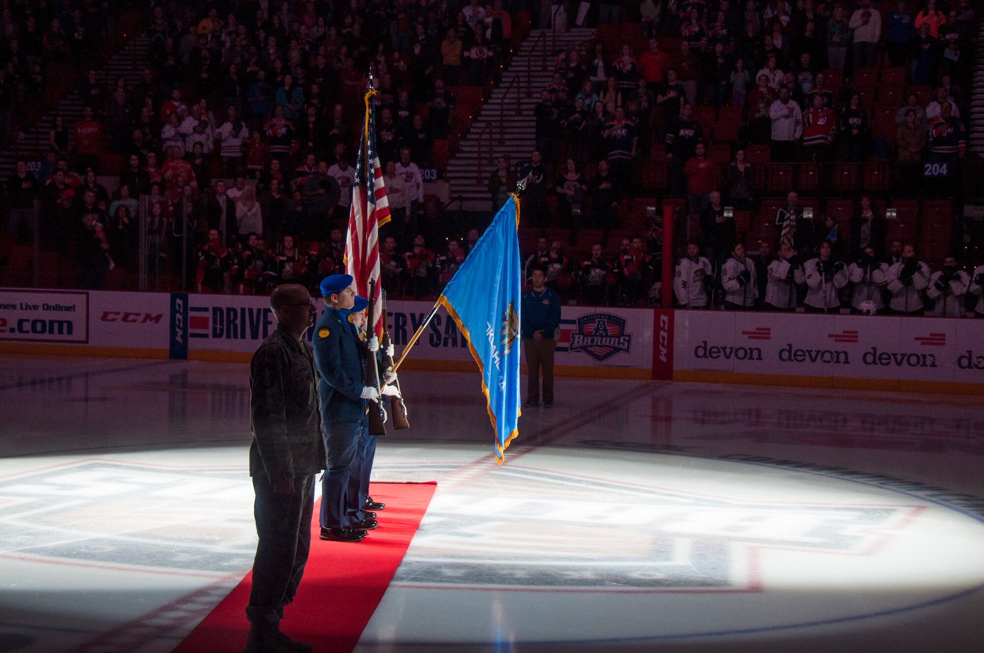 Senior Master Sergeant Robert Gaspar stands at attention for the national anthem before the start of the Oklahoma City Barons game Saturday March 15, 2014.  Gaspar took his final Oath of Enlistment prior to the game.  Also on hand presenting the colors was the Midwest City AFJROTC.  Senior Master Sergeant Gaspar’s re-enlistment will give him 34 years of service marking the end of his career.  Gaspar, a long time Barons season ticket holder, said taking the oath at center ice was nerve wracking, but also one of his career highlights.  (U.S. Air Force photo/Senior Airman Mark Hybers)     