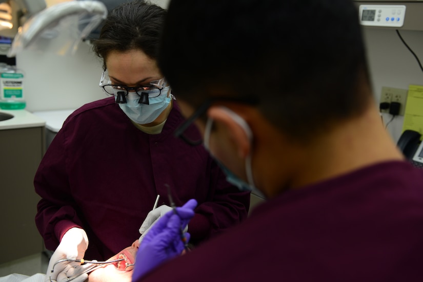 U.S. Air Force Capt. Julie Anderson, 633rd Dental Squadron advanced educational general dentistry resident and Airman 1st Class Jacob Yglecias, 633rd DS dental assistant, perform a dental procedure at Langley Air Force Base, Va., March 13, 2014. Anderson is part of the AGED program, a one-year residency that provides new dentists clinical, in-class and hospital experience at the post-doctoral level.  Anderson hails from Florence, Ky. and Yglecias from El Paso, Texas. (U.S. Air Force photo by Airman 1st Class Kimberly Nagle/Released)