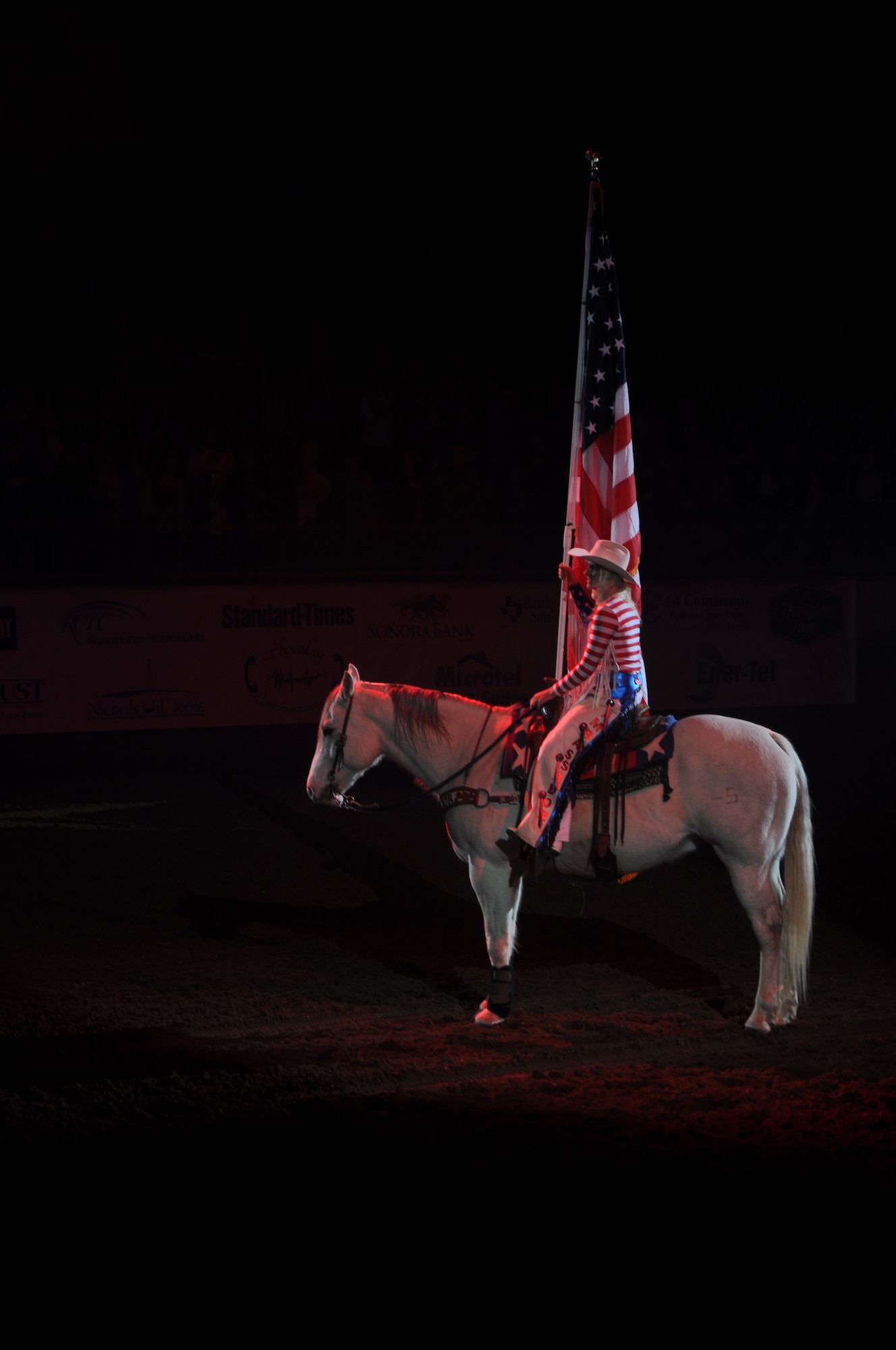 SAN ANGELO, Texas – Marissa Griffin, San Angelo Stock Show and Rodeo Drill Team ambassador, presents the American Flag at the beginning of the San Angelo Stock Show and Rodeo’s Military Appreciation Night at the Foster Communication Coliseum here Feb. 26. Goodfellow Air Force Base’s  Patriotic Blue sang the national anthem during the flag presentation. (U.S. Air Force photo/ Airman 1st Class Breonna Veal)