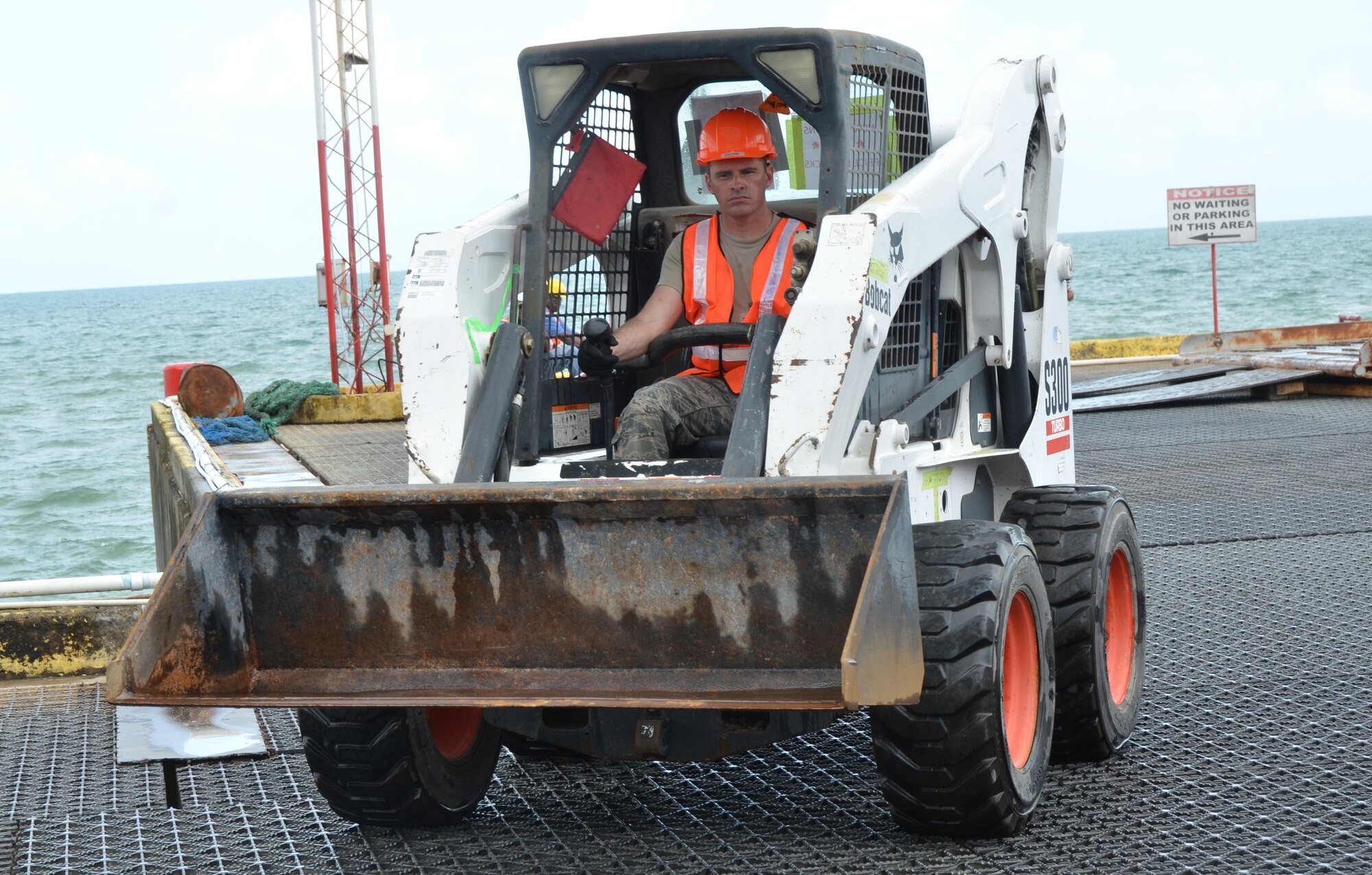 Tech. Sgt. Lance Beaver, New Horizons air transportation craftsman, drives a Bobcat off of the barge and onto the pier March 8. (U.S. Air Force photo by Master Sgt. Kelly Ogden/Released)