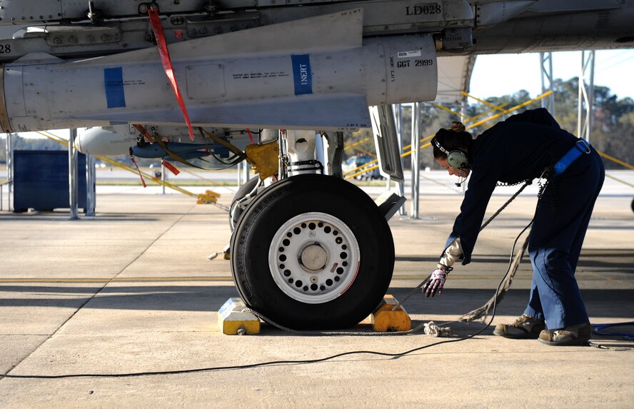 U.S. Air Force Senior Airman Grace Wheeler, 74th Aircraft Maintenance Unit crew chief, removes the tire chocks from an A-10C Thunderbolt II at Moody Air Force Base, Ga., March 14, 2014. After pre-flight inspections, tire chocks are removed to prepare the pilot for takeoff. (U.S. Air Force photo by Senior Airman Olivia Bumpers/Released) 