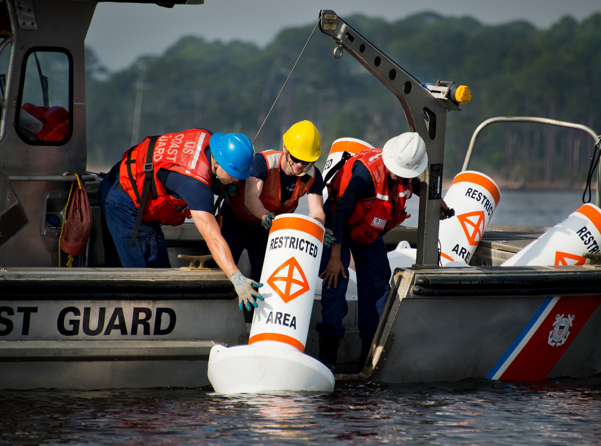 Seaman Dustin Mark, Petty Officers 3rd Class Tyler O’Connor and Dewaine Harris, Aids to Navigation Team members from Coast Guard Station Pensacola, place a restricted area buoy in the water March 11 at Eglin Air Force Base, Fla.  The Coast Guard posted approximately 40 buoys along the base’s coastline from Post’l Point to the Bayview Club.  The anchored buoys, spread approximately 700 feet from each other, are a force protection enterprise by the base to identify Eglin waterways.  According to the code of federal regulations (CFR 334.700-748), all vessels and other craft are permitted access to the restricted area, but could be subject to identification checks by Air Force patrol boats.  During times of high security threats against Eglin or Hurlburt Field, all entry, transit, anchoring or drifting within the restricted areas is prohibited without permission from the respective base commander or authorized representative.  (U.S. Air Force photo/Samuel King Jr.)