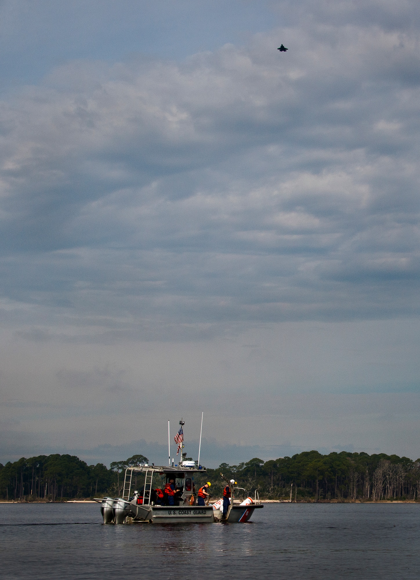 Aids to Navigation Team members from Coast Guard Station Pensacola prepare to post a restricted area buoy as an F-35 Lightning II flies overhead March 11 at Eglin Air Force Base, Fla.  The Coast Guard posted approximately 40 buoys along the base’s coastline from Post’l Point to the Bayview Club.  The anchored buoys, spread approximately 700 feet from each other, are a force protection enterprise by the base to identify Eglin waterways.  According to the code of federal regulations (CFR 334.700-748), all vessels and other craft are permitted access to the restricted area, but could be subject to identification checks by Air Force patrol boats.  During times of high security threats against Eglin or Hurlburt Field, all entry, transit, anchoring or drifting within the restricted areas is prohibited without permission from the respective base commander or authorized representative.  (U.S. Air Force photo/Samuel King Jr.)