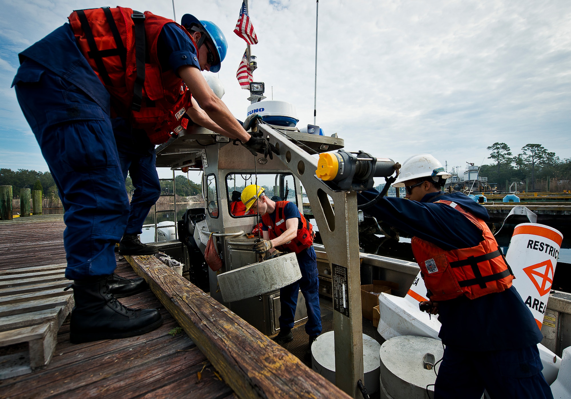 Aids to Navigation Team members from Coast Guard Station Pensacola move anchors onto their boat along with restricted waterway buoys March 11 at Eglin Air Force Base, Fla.  The Coast Guard posted approximately 40 buoys along the base’s coastline from Post’l Point to the Bayview Club.  The anchored buoys, spread approximately 700 feet from each other, are a force protection enterprise by the base to identify Eglin waterways.  According to the code of federal regulations (CFR 334.700-748), all vessels and other craft are permitted access to the restricted area, but could be subject to identification checks by Air Force patrol boats.  During times of high security threats against Eglin or Hurlburt Field, all entry, transit, anchoring or drifting within the restricted areas is prohibited without permission from the respective base commander or authorized representative.  (U.S. Air Force photo/Samuel King Jr.)