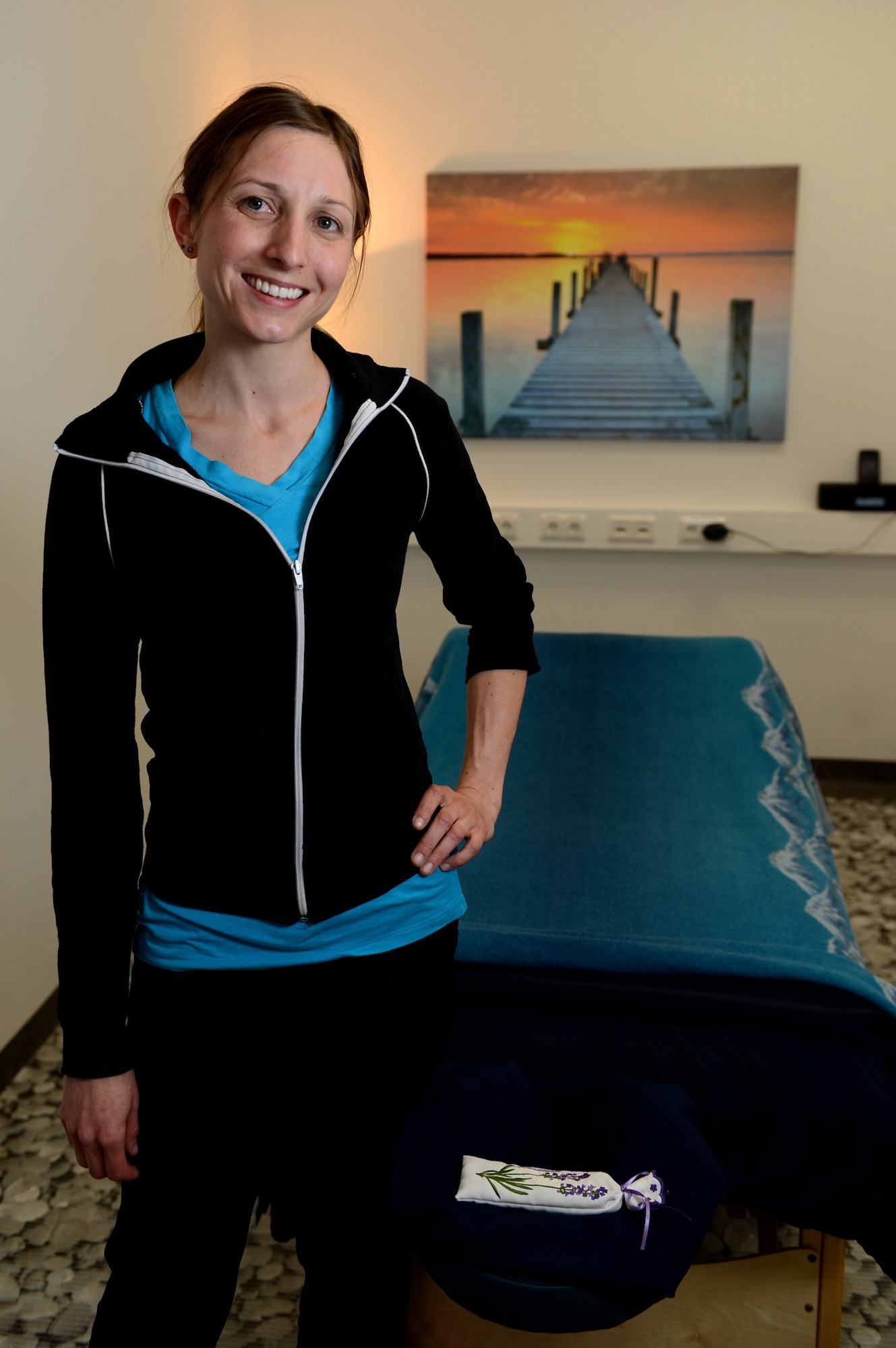 Andrea Trebesh, a massage therapist from Colorado Springs, Colo., stands in front of her massage table at Spangdahlem Air Base, Germany, March 14, 2014. Trebesh is a licensed therapist who applies her knowledge of sports and physical activity to help determine which muscles need attention. (U.S. Air Force photo by Airman 1st Class Kyle Gese/Released)