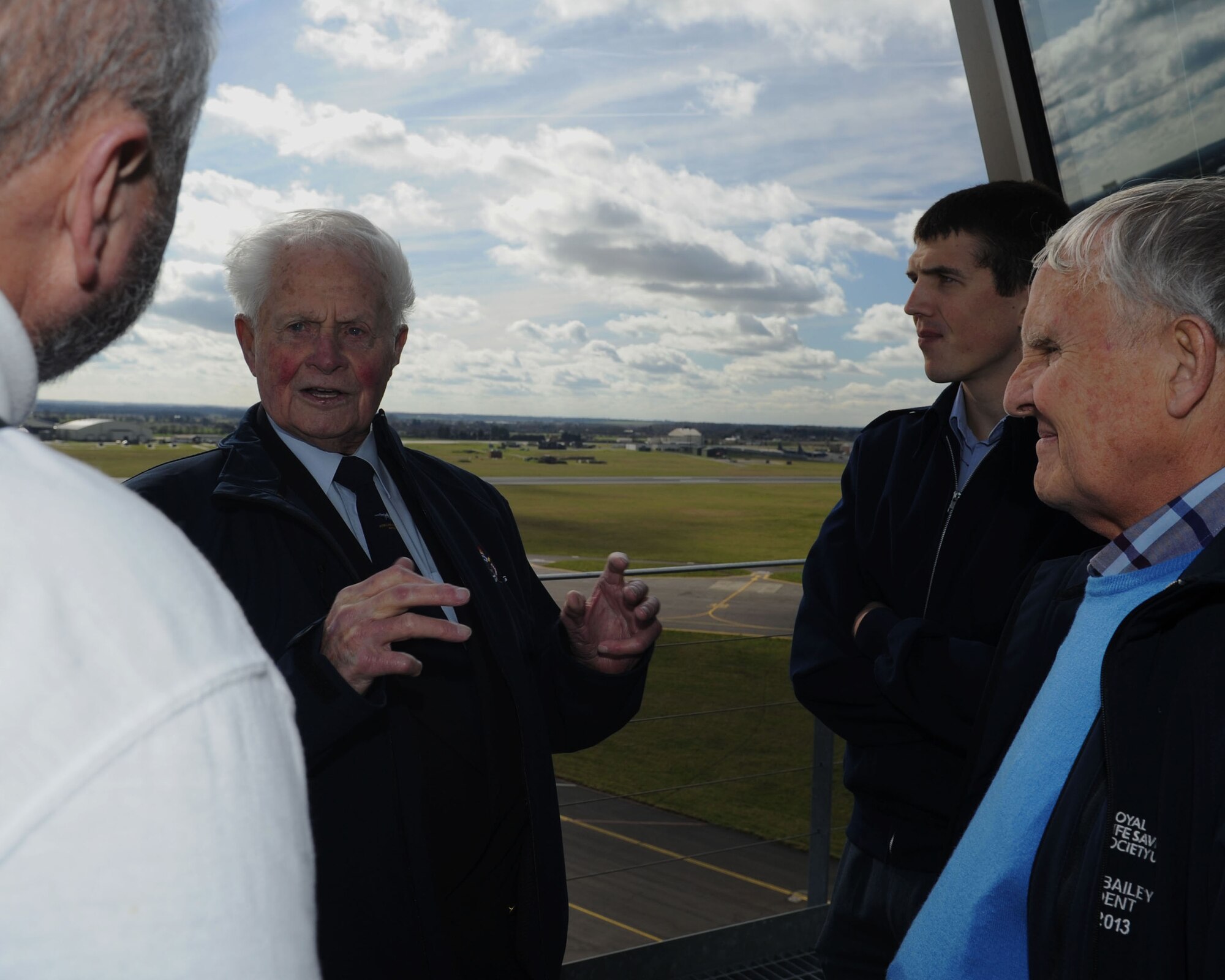 Maurice Howard Bailey, second from left, former prisoner of war during World War II and former Royal Air Force No. 15 Squadron wireless operator, explains what he remembers about RAF Mildenhall to Mark Howell, left, 100th Air Refueling Wing historian; RAF Cpl. Peter Anthony Beynon, second from right, a nurse with Princess Mary’s RAF Nurses; and Stuart Bailey, right, Bailey’s son, March 7, 2014, on RAF Mildenhall, England. Bailey described how the runway used to have a hump that would damage aircraft if they tried to take off too quickly. Bailey toured the base as the last surviving member of his former crew. (U.S. Air Force photo by Airman 1st Class Preston Webb/Released)