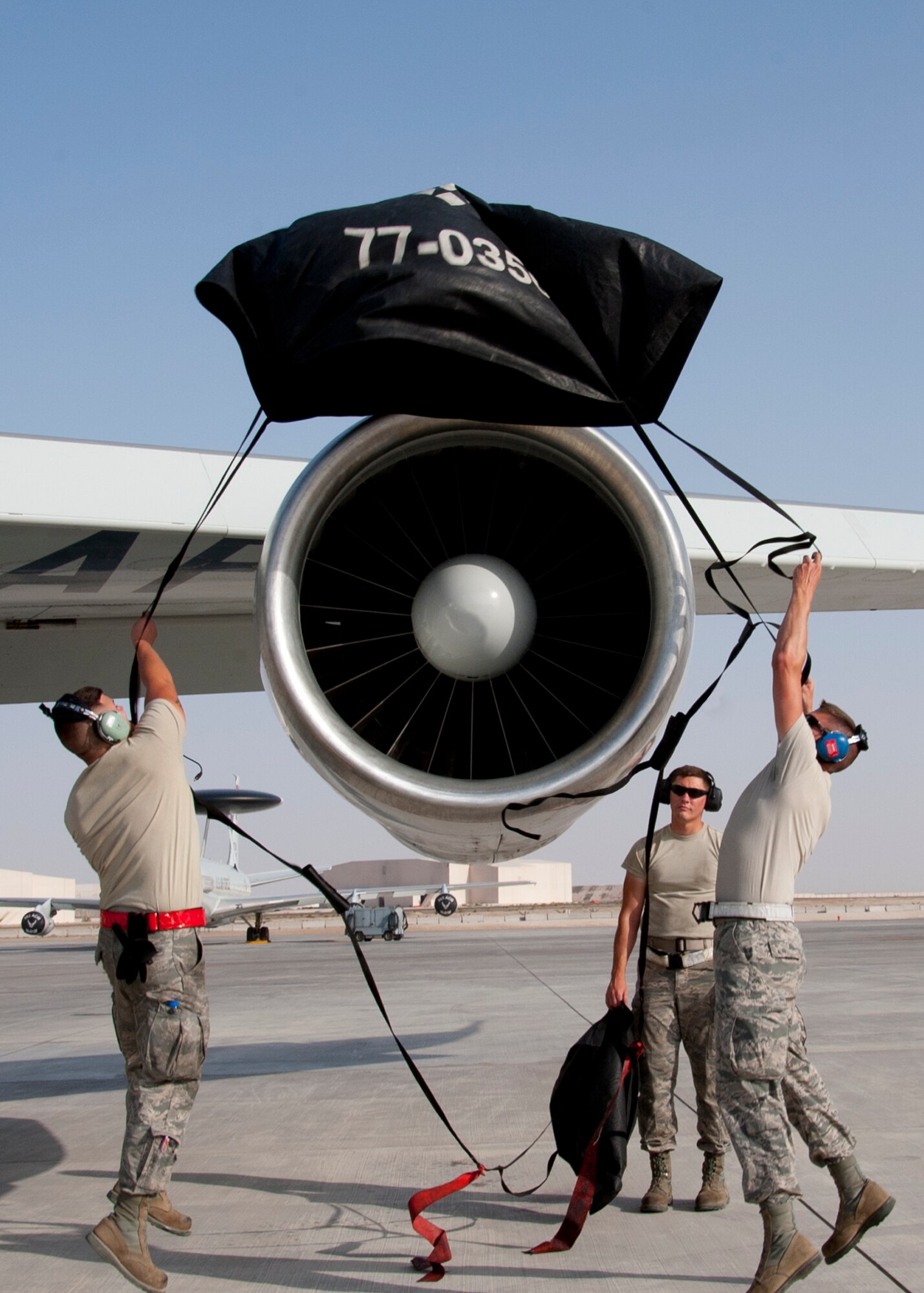 Air Force Senior Airman Nicholas Wisor and Air Force Senior Airman Adam Cannon, both E-3 communication and navigation technicians assigned to the 380th Expeditionary Aircraft Maintenance Squadron Sentry Aircraft Maintenance Unit, installs an engine cover on an E-3 Sentry at an undisclosed location in Southwest Asia, March 12, 2014. Both Airmen are deployed from Tinker Air Force Base, Okla. (U.S. Air Force photo by Staff Sgt. Michael Means/Released)