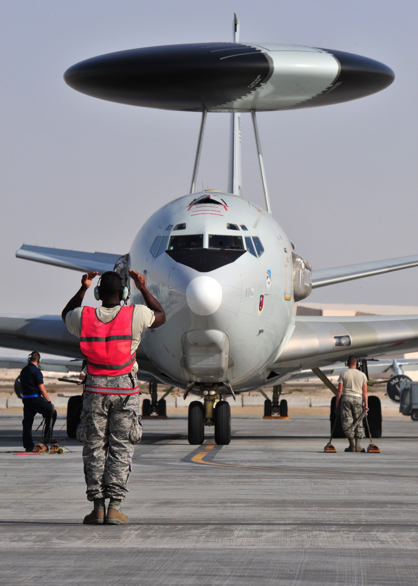 Air Force Staff Sgt. Clifford Scott, 380th Expeditionary Aircraft Maintenance Squadron Sentry Aircraft Maintenance Unit E-3 computers technician, marshals in an E-3 Sentry at an undisclosed location in Southwest Asia, March 12, 2014. Scott is a native of Baltimore, Md., and is deployed from Tinker Air Force Base, Okla. (U.S. Air Force photo by Staff Sgt. Michael Means/Released)