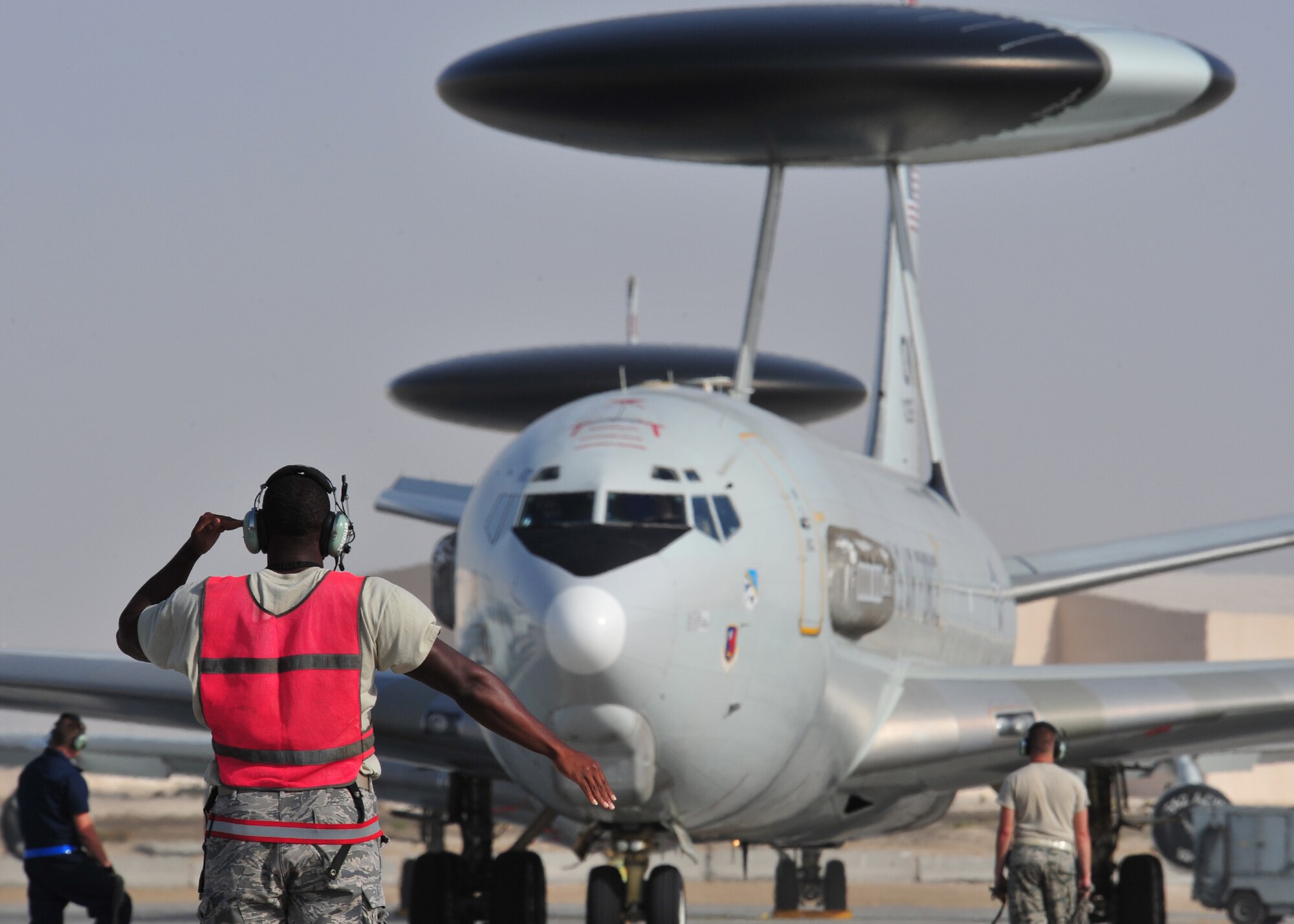 Air Force Staff Sgt. Clifford Scott, 380th Expeditionary Aircraft Maintenance Squadron Sentry Aircraft Maintenance Unit E-3 computers technician, marshals in an E-3 Sentry at an undisclosed location in Southwest Asia, March 12, 2014. Scott is a native of Baltimore, Md., and is deployed from Tinker Air Force Base, Okla. (U.S. Air Force photo by Staff Sgt. Michael Means/Released)