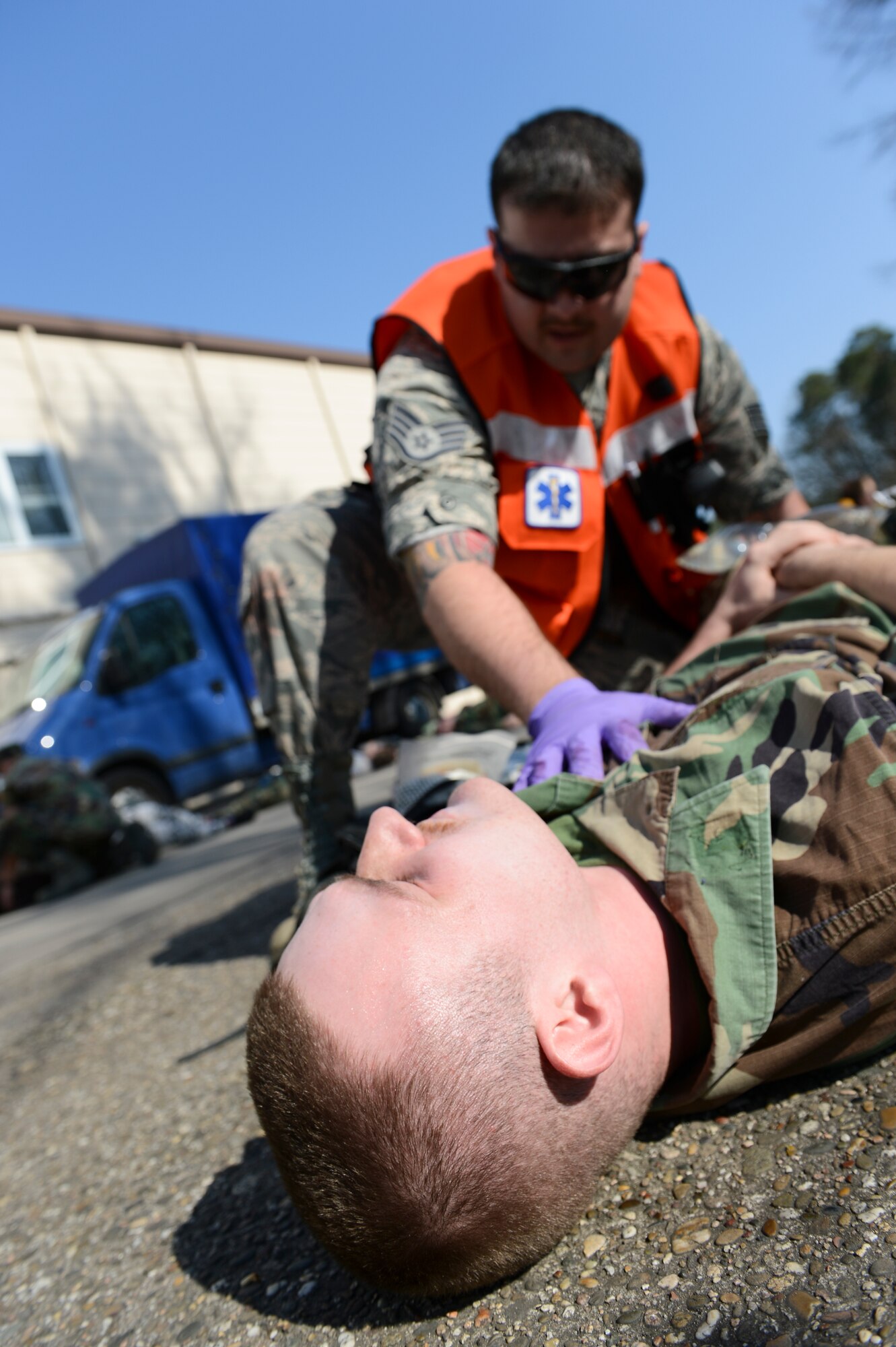 A mass casualty training victim simulates pain that he is experiencing while a first responder tends to his burns and wounds March 13, 2014, Ramstein Air Base, Germany. A first responder must provide immediate care to a victim as quickly when arriving on scene. The 86th Medical Group hosted a mass casualty training to familiarize first responders with the scene of a disaster or a catastrophe. (U.S. Air Force Photo/Airman 1st Class Michael Stuart)