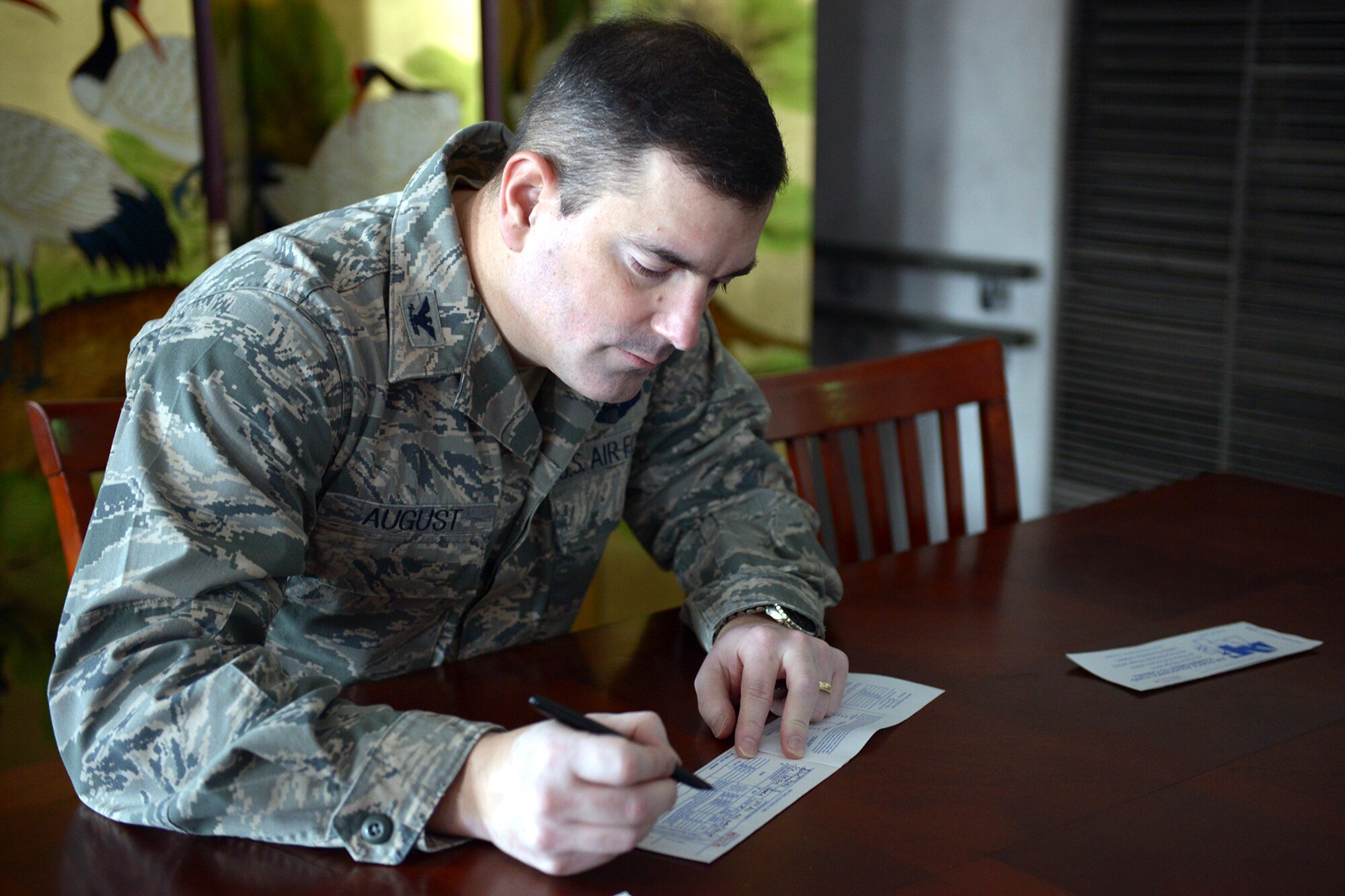 Col. Mark August, 374th Airlift Wing commander, signs a pledge to the Air Force Assistance Fund (AFAF) at Yokota Air Base, Japan, March 17, 2014. The AFAF was established to raise funds for the charitable affiliates that provide support to the Air Force family in need. (U.S. Air Force photo by Airman 1st Class David Danford/Released)