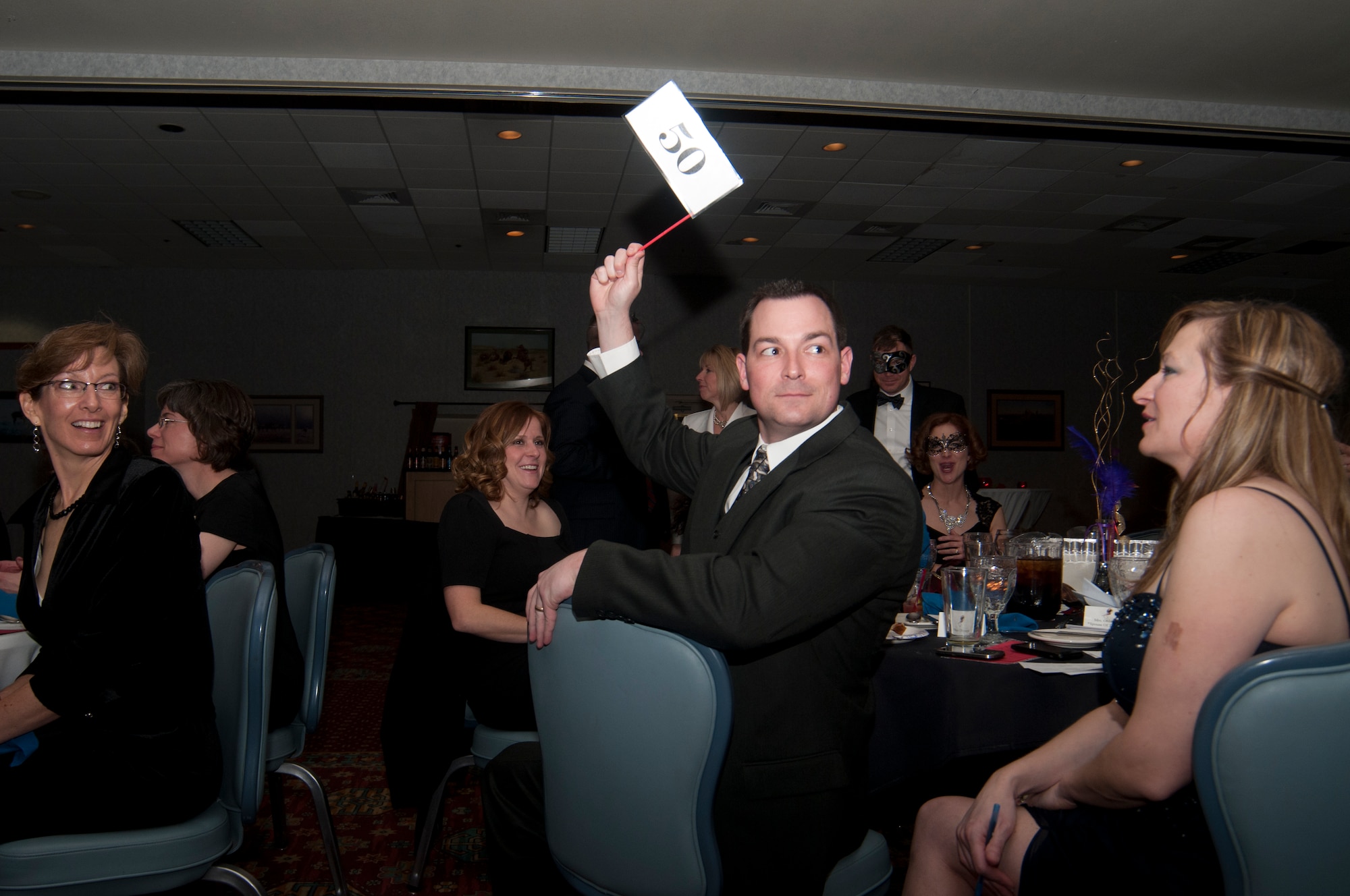 Maj. Steven Ohlmeyer, 90th Security Forces Squadron commander, bids on an item during the live auction portion of the 8th Annual Warren Spouses Club Basket Auction & Masquerade March 15, 2014, in the Trail’s End Club. The $13,318 raised at the auction will fund WSC scholarships. (U.S. Air Force photo by Airman 1st Class Jason Wiese)