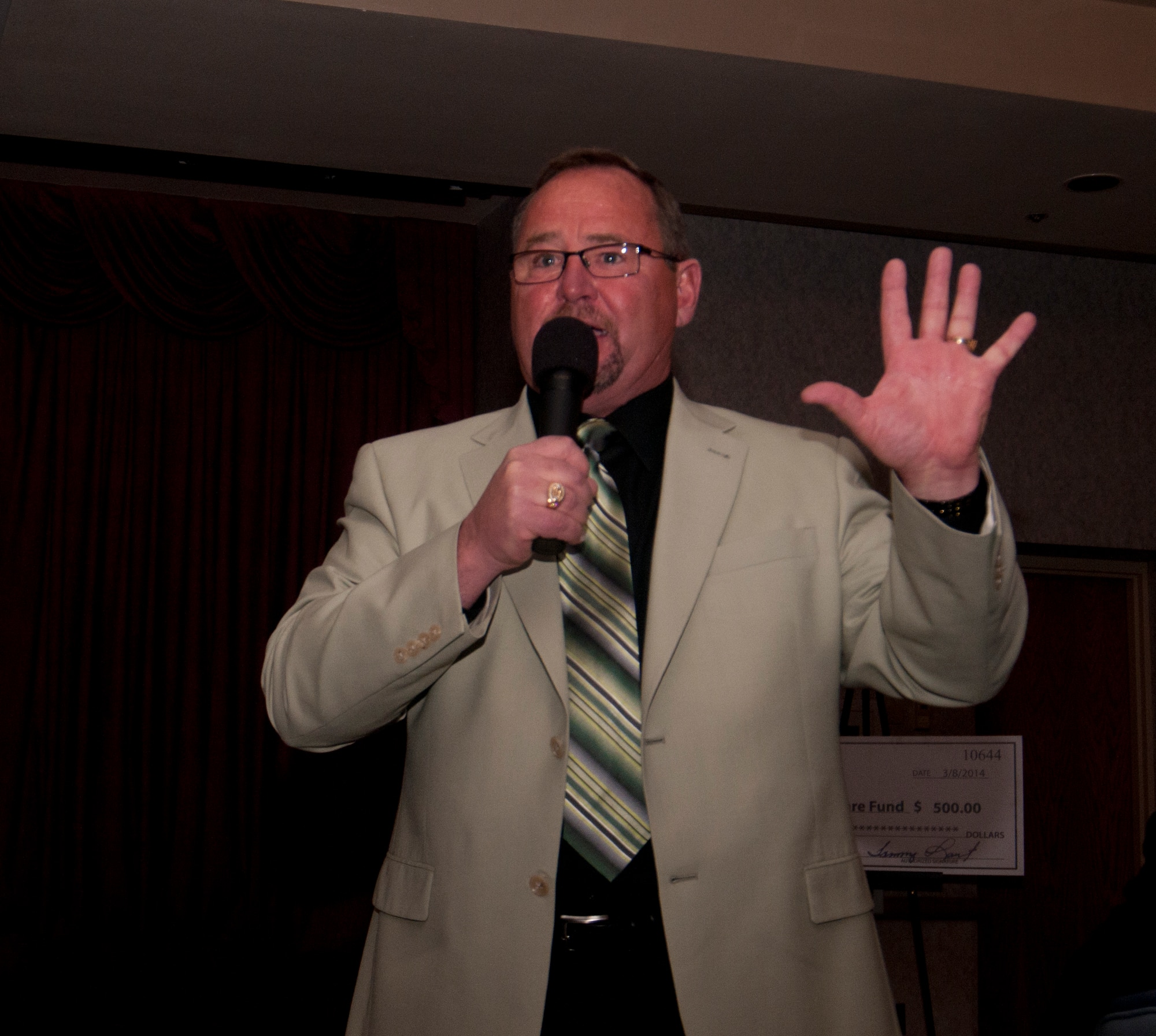 Dean Gunter, auctioneer, auctions off a dessert during the 8th Annual Warren Spouses Club Basket Auction & Masquerade March 15, 2014, in the Trail’s End Club. (U.S. Air Force photo by Airman 1st Class Jason Wiese)
