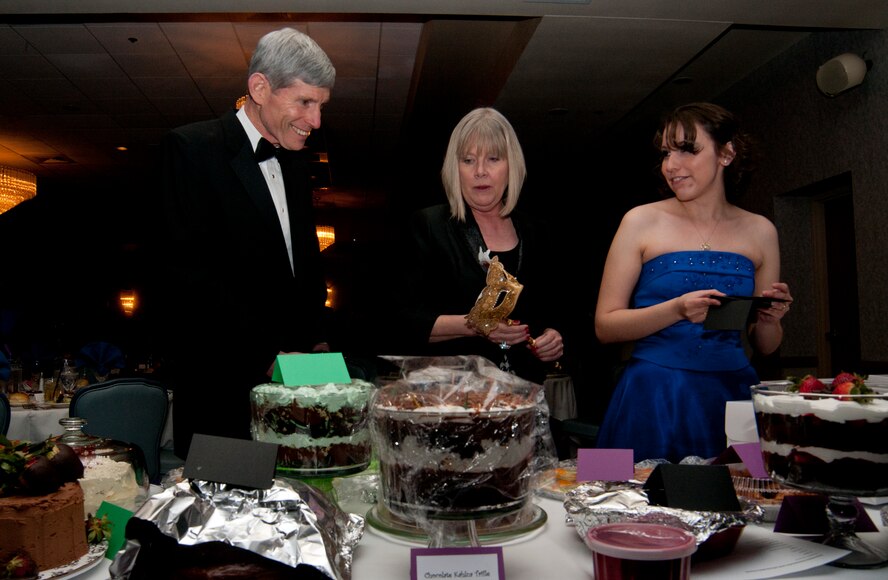 Former Air Force Chief of Staff, Gen. (Ret.) Norton A. Schwartz; his wife, Suzie Schwartz, military family advocate; and Linda Ortega, Warren Spouses Club member, discuss the desserts up for auction during the dessert portion of the 8th Annual WSC Basket Auction & Masquerade March 15, 2014, in the Trail’s End Club. The live auction portion of the event began with tables bidding on desserts to be shared during the auctioning of the baskets later in the evening. (U.S. Air Force photo by Airman 1st Class Jason Wiese)