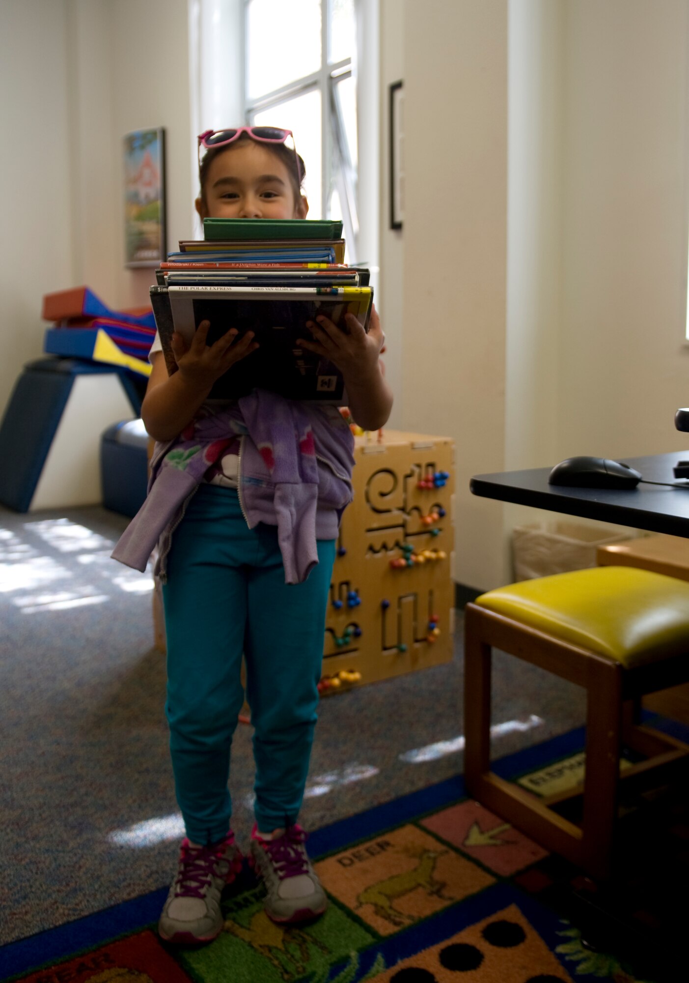 Kaitlyn Thomas, 6, daughter of Tech. Sgt. Bryan Thomas, 823rd RED HORSE Squadron, carries her books in the children’s section of the base library at Hurlburt Field, Fla., March 18, 2014. She said she loves books because they teach her a lot of words. (U.S. Air Force photo/Senior Airman Naomi Griego)    