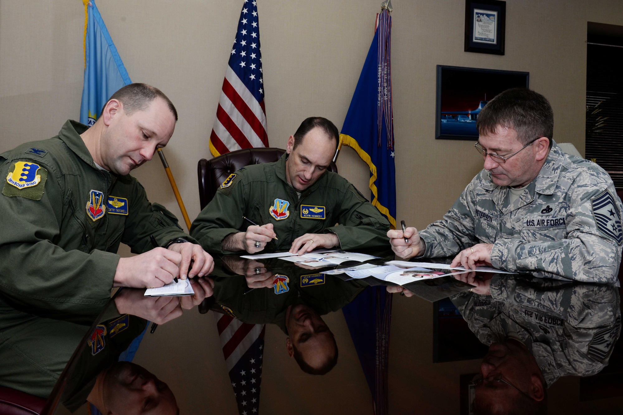 Col. Gentry Boswell, 28th Bomb Wing vice commander, (left) Col. Kevin Kennedy, 28th BW commander, and Chief Master Sgt. Kevin Peterson, 28th BW command chief, sign the first donation slips for the 2014 Air Force Assistance Fund campaign at Ellsworth Air Force Base, S.D., March 17, 2014. The AFAF campaign provides Airmen with an opportunity to donate to charities benefiting active duty, retired, office and enlisted Airmen. (U.S. Air Force photo by Airman 1st Class Rebecca Imwalle/ Released)
