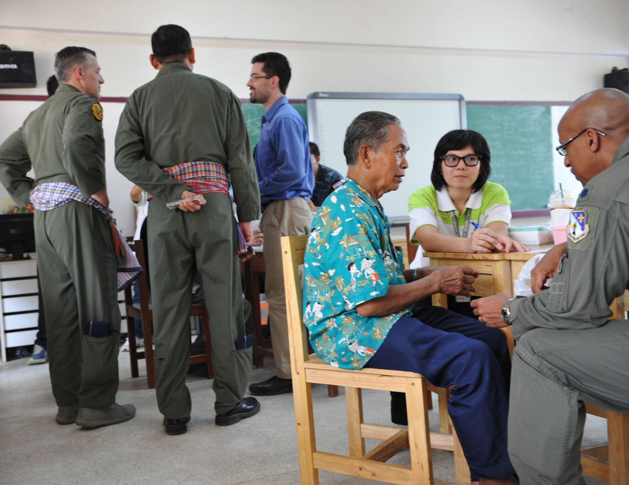 Air Force Lt. Col. Phillip Lundy, flight surgeon with the 159th Fighter Wing, Naval Air Station Joint Reserve Base New Orleans, sees a patient during a medical civic action event in Dan Kwian village near Korat, Thailand while Col. John Traettino consults with the Thai and Singapore co-directors of Cope Tiger 2014. The civic action event was part of an engagement with the Dan Kwian Witthaya School, where U.S., Singapore and Thai Air Force members offered community medical and dental services and exchanged culture with the local school children as part of the multi-week annual Pacific Air Forces exercise. (U.S. Air Force photo by 2Lt. Michael Harrington/Released)