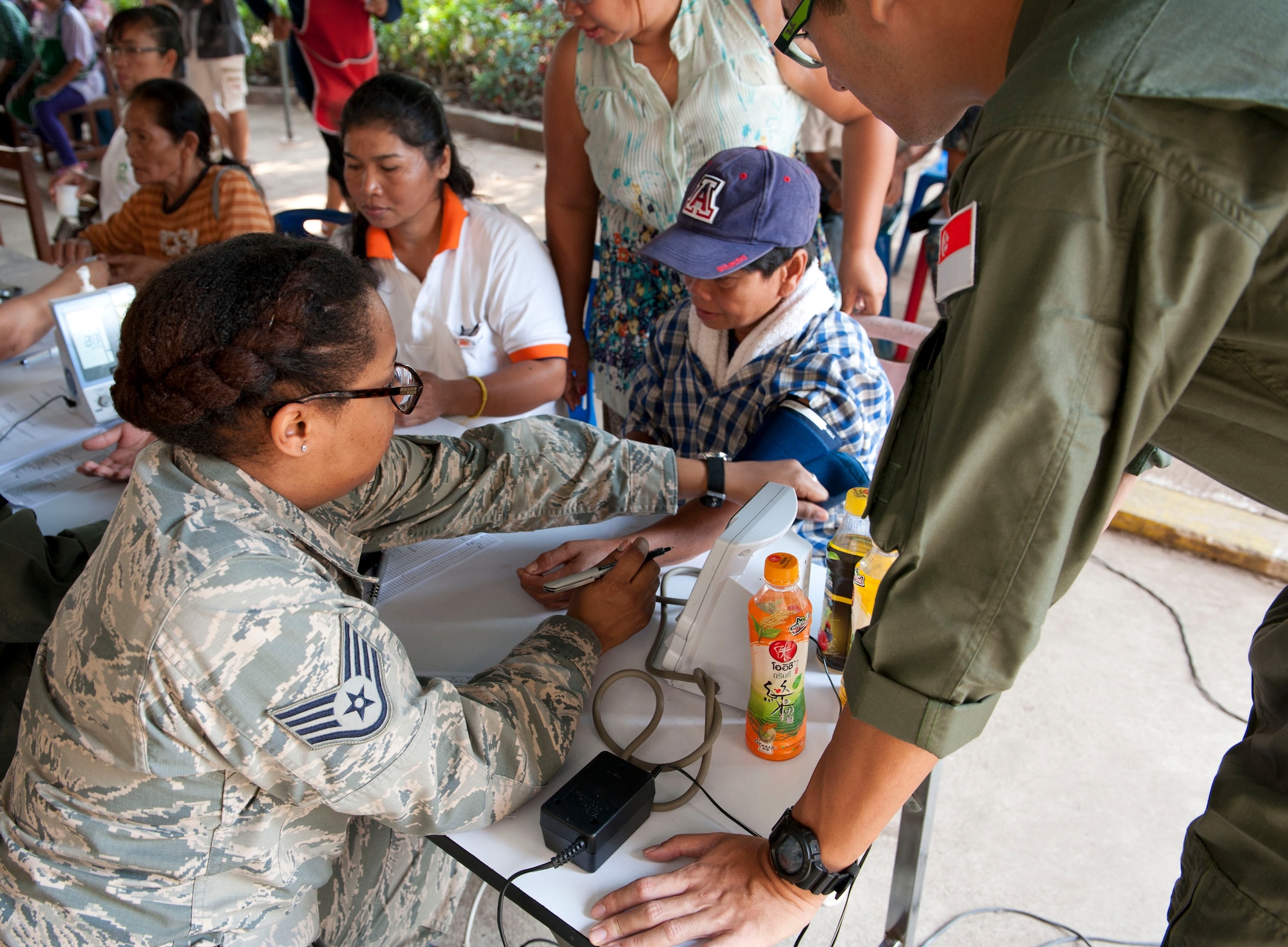 Staff Sgt. Tasia Bradley, medical technician, Naval Air Station Joint Reserve Base New Orleans, and a Republic of Singpore aeromedical technician collect a patient's vitals during a medical civic action program in Dan Kwian village, Korat, Thailand. The civic action event was part of an engagement with the Dan Kwian Witthaya School, where U.S., Singapore and Thai Air Force members offered community medical and dental services and exchanged cultures with the local school children as part of exercise Cope Tiger 2014. (U.S. Air Force photo by 2Lt. Michael Harrington/Released)