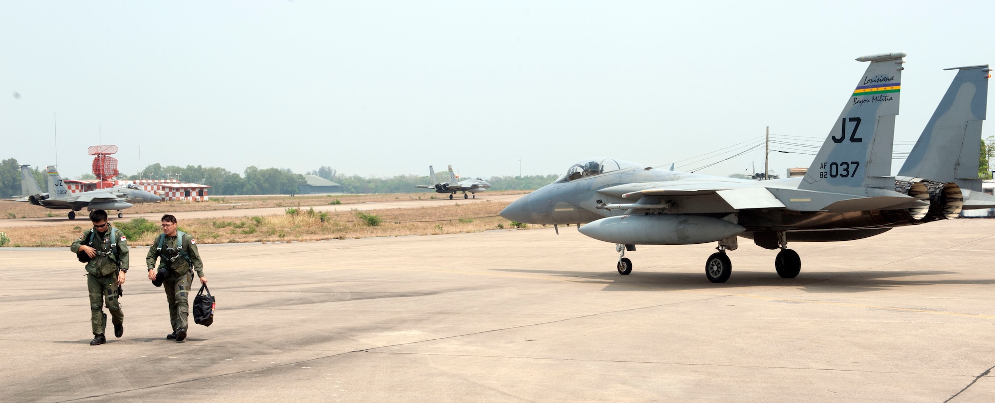 Two Republic of Singapore Air Force pilots head to their aircraft as fellow F-15 Eagle pilot U.S. Air Force Maj. Sheldon Gardener, Naval Air Station Joint Reserve Base New Orleans, taxis past them to the runway. Two other F-15's from the Louisiana Air National Guard are visible gearing for takeoff in the background. Cope Tiger 2014 is an annual, mulilateral aerial exercise to improve combat readiness, interoperability and build relations among Thai, Singapore and U.S. air forces. (U.S. Air Force photo by 2Lt. Michael Harrington/Released)