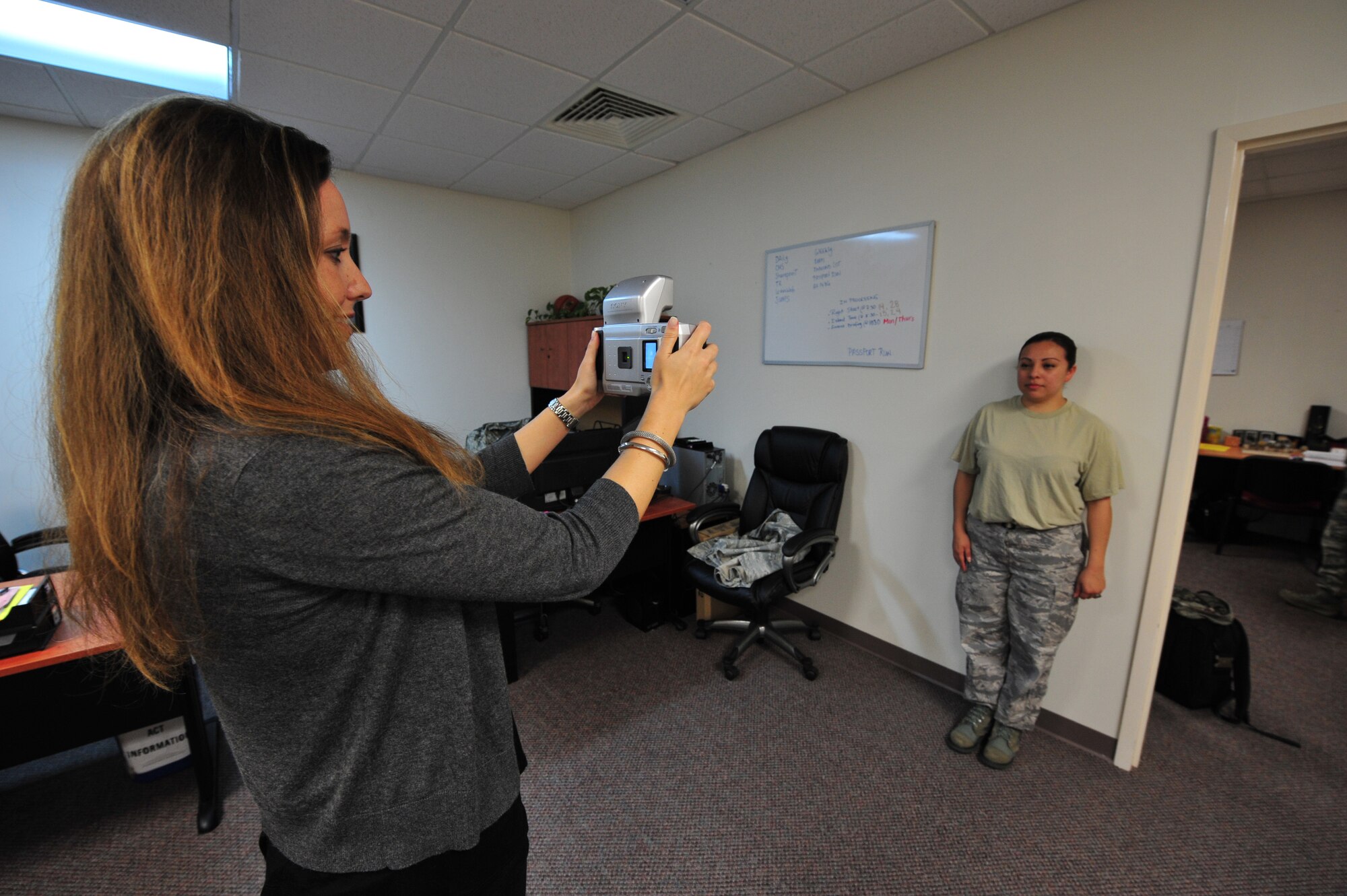 Catia Sebastiao, 65th Force Support Squadron Military Personnel Section, assists Staff Sgt. Lizabeth Vaquero with an official passport photo, May 5, 2013, Lajes Field, Azores. For the second year in a row, the 65th FSS was awarded the Maj. Gen. Eugene L. Eubank Award at the Air Force level for 2013. They won the same award at the U.S. Air Forces in Europe level in 2011, 2012 and 2013. (U.S. Air Force photo by Tech. Sgt. Chenzira Mallory/released)
